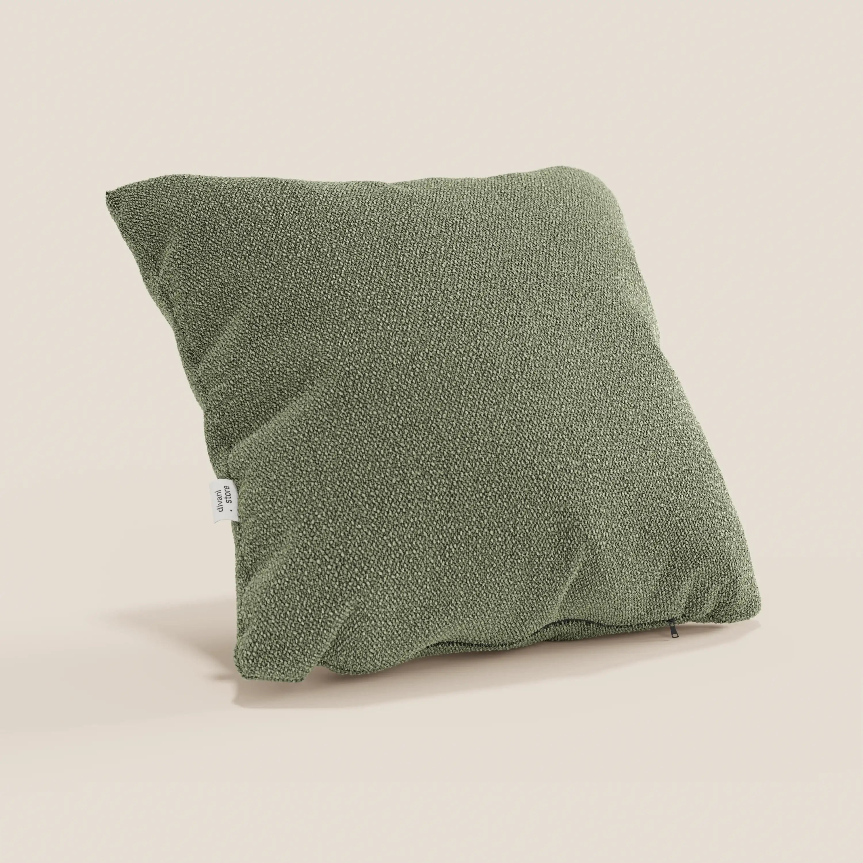 Il cuscino Lambada di Divani.Store, presentato in un tenue verde oliva su sfondo beige, presenta un design strutturato e squadrato in tessuto lavabile e impermeabile che imita il cotone naturale, con una targhetta laterale e delicate ombre che ne accentuano l'aspetto felpato.