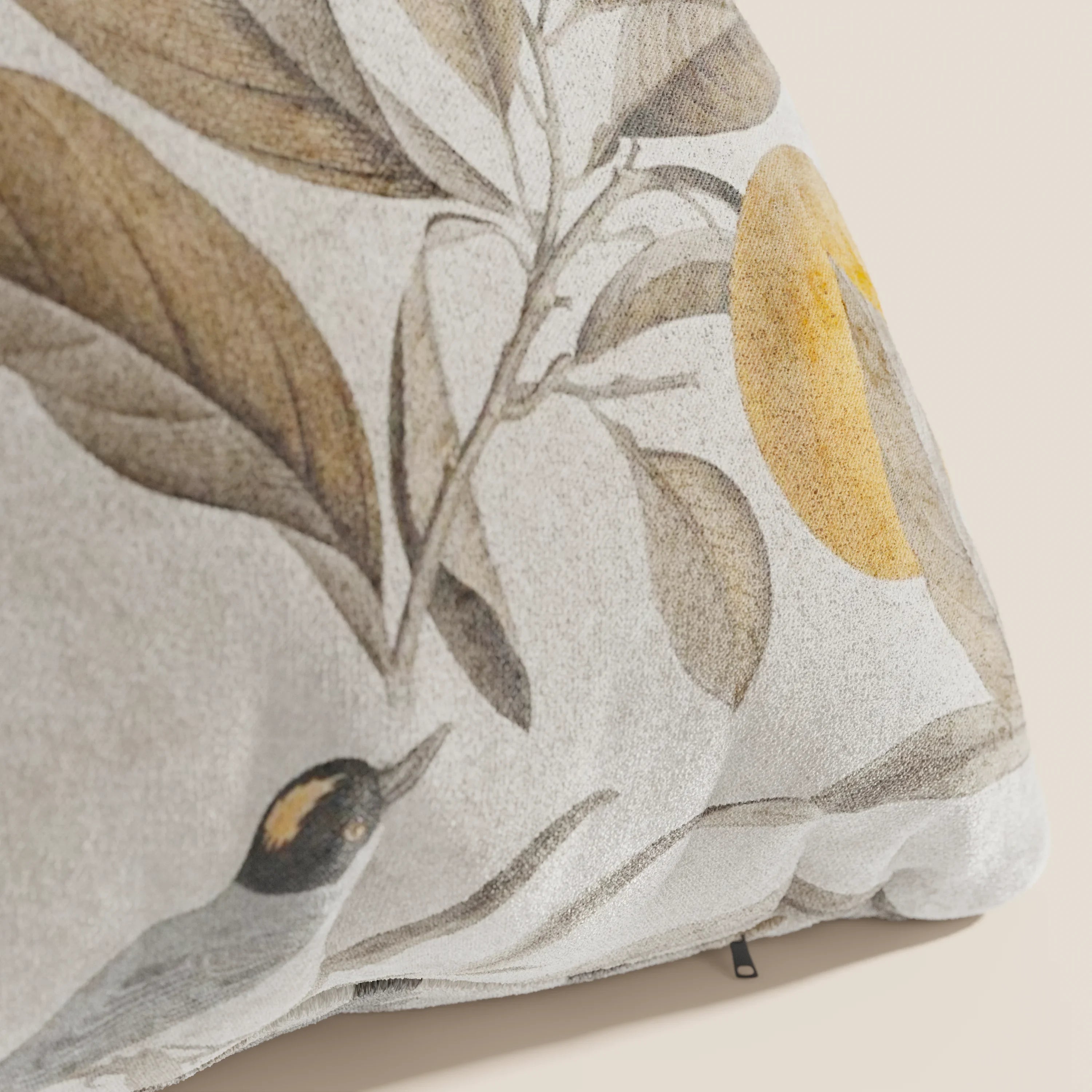 Primo piano di Lemon elegante collezione di cuscini a fantasia in velluto impermeabile beige di Divani.Store, con foglie marroni, un sole o una luna gialli e un uccello giallo e nero per un look ispirato alla natura nei toni tenui della terra.