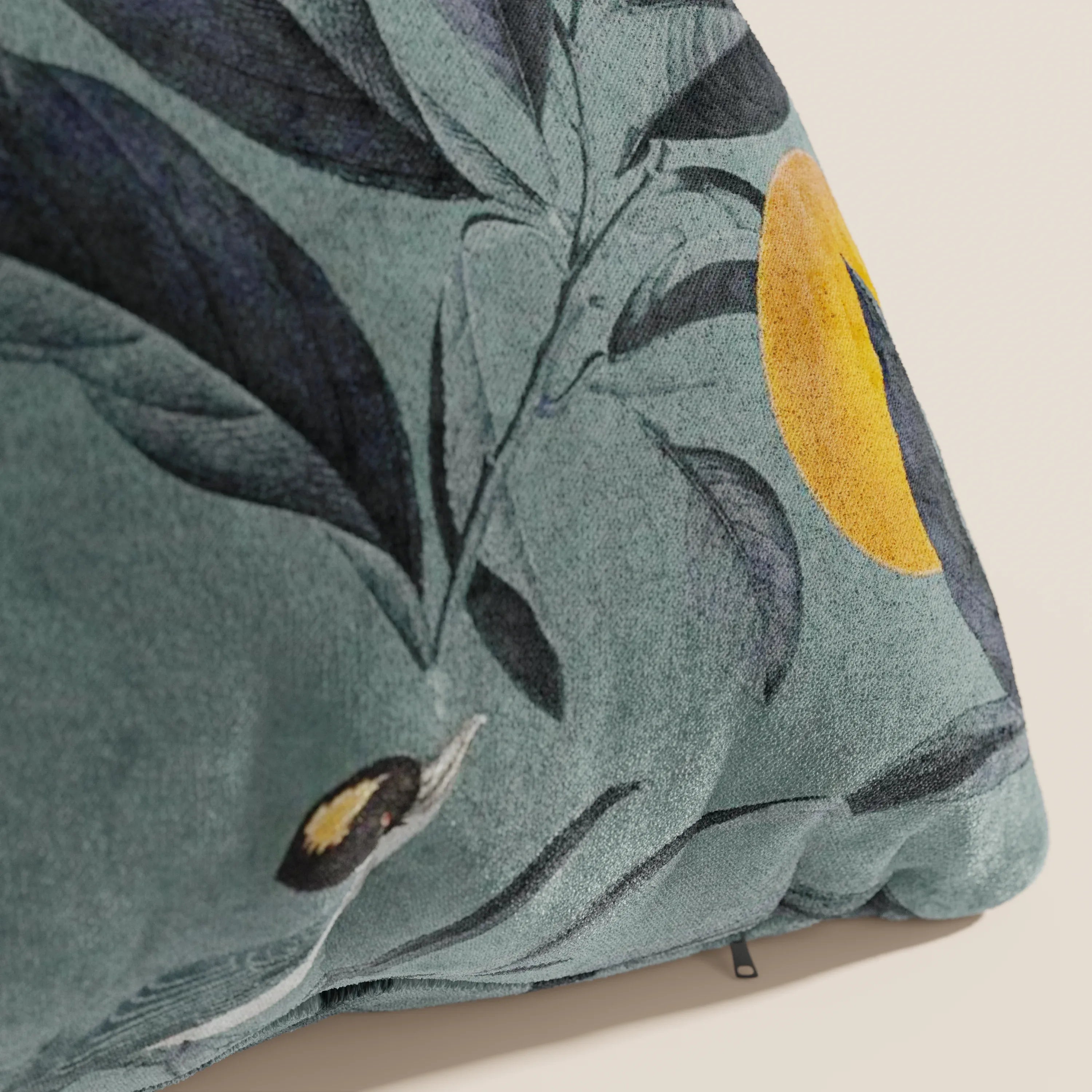 Un primo piano del cuscino Lemon elegante a fantasia in velluto impermeabile petrolio di Divani.Store, che mostra stampe botaniche blu scuro, un cerchio giallo e parte di un uccello, uno dei nostri cuscini decorativi lavabili.