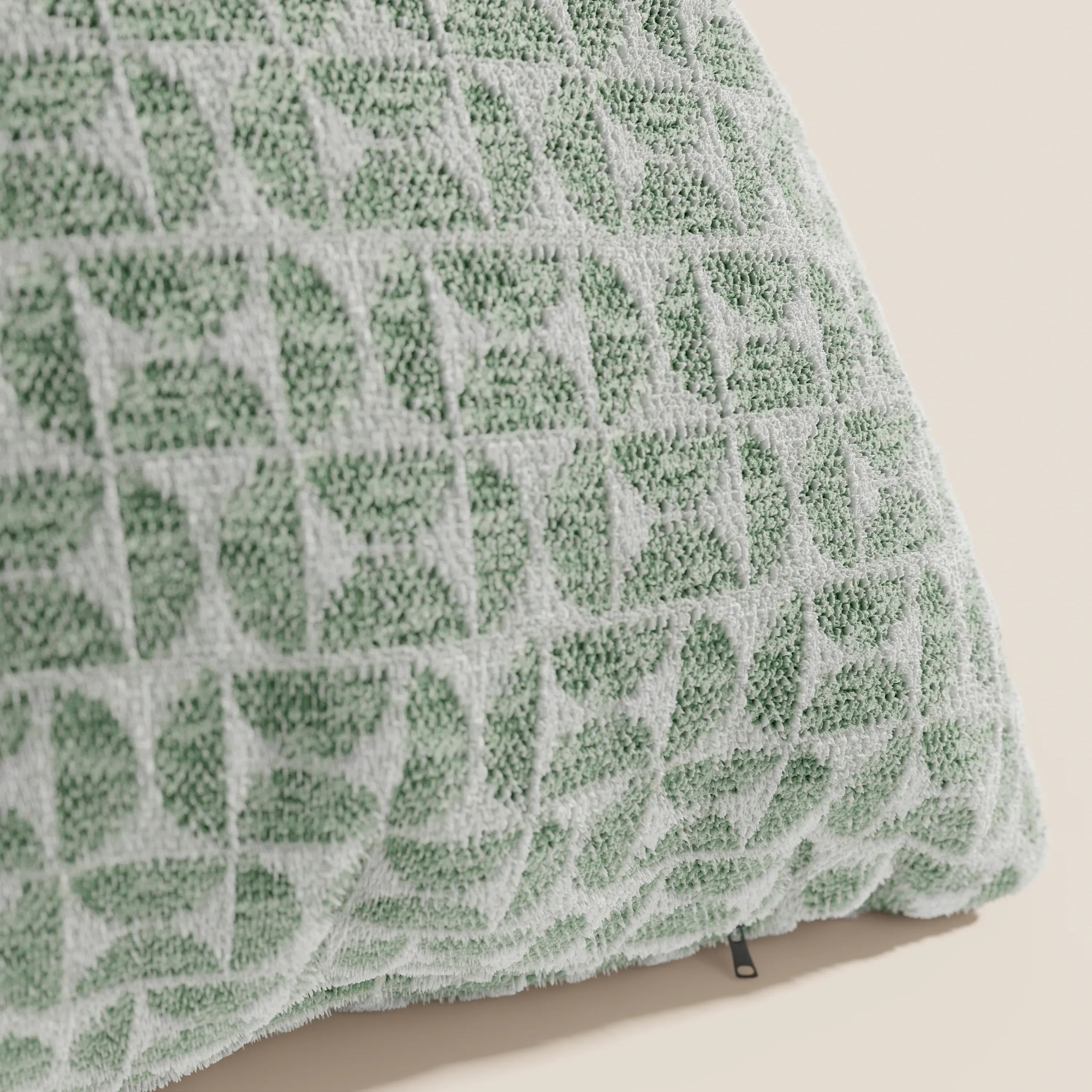 Primo piano del cuscino Naxos Cuscino Decoro 45x45 in lino di Divani.Store, caratterizzato da un tessuto in lino testurizzato con motivi geometrici a girandola nei toni del verde chiaro e del bianco sporco. Un'etichetta nera mette in risalto questo elegante cuscino quadrato su uno sfondo neutro.