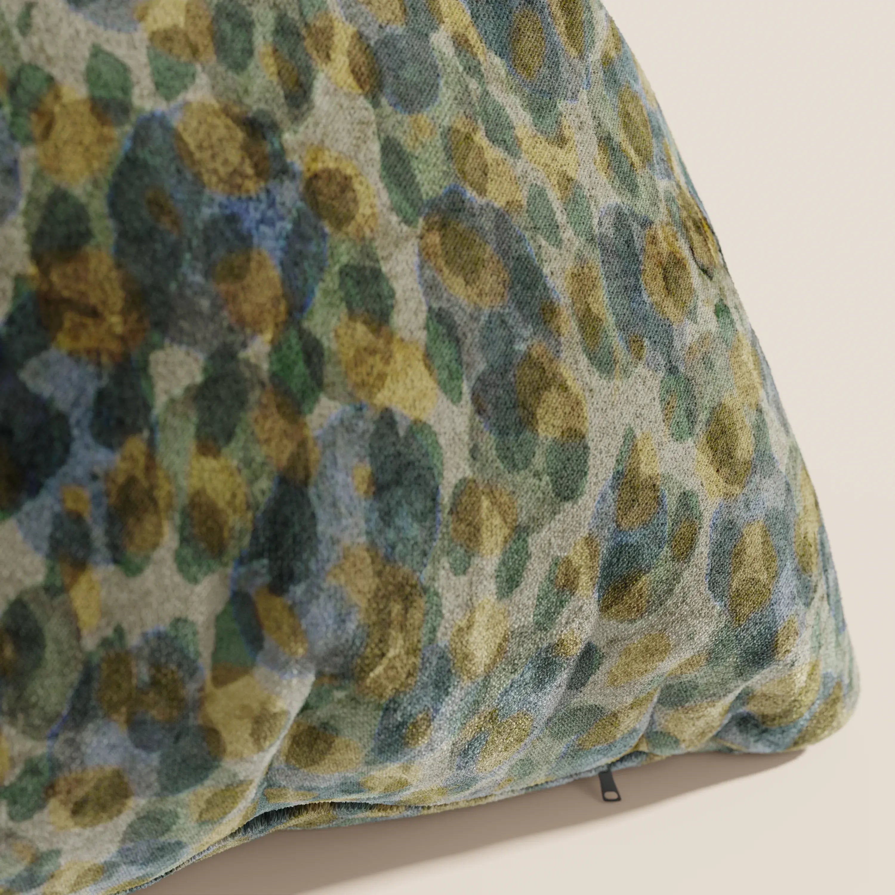 Un primo piano del cuscino Brush di Divani.Store, un cuscino decorativo 45x45 in velluto verde impermeabile con un motivo astratto, appoggiato su una parete semplice di colore bianco sporco.