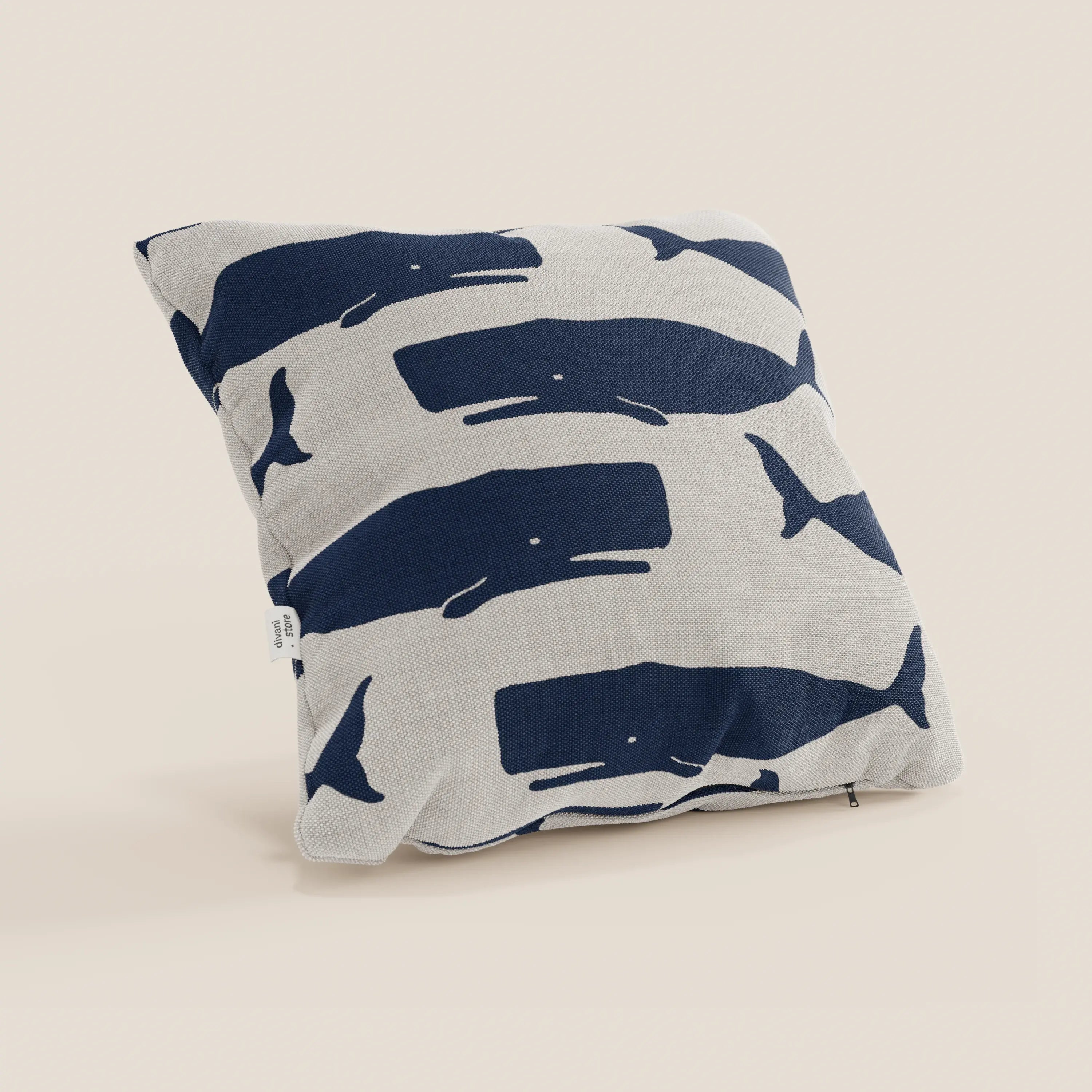 Il cuscino quadrato Nautilus di Divani.Store, in tessuto impermeabile, presenta balene blu su sfondo beige e un'etichetta bianca; perfetto per aggiungere stile marino alla tua casa.