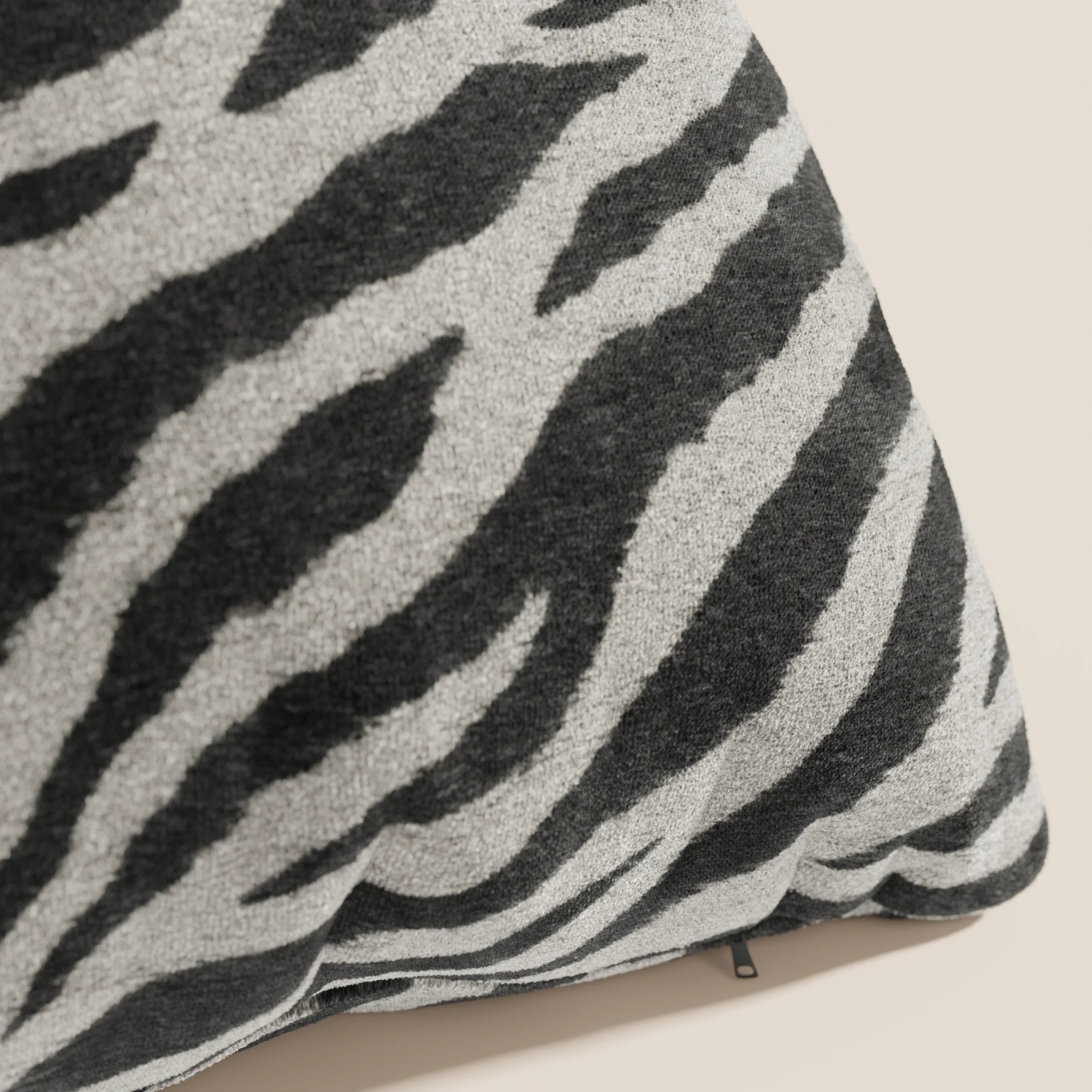 Primo piano del cuscino Wild 45x45 della collezione Wild di Divani.Store, caratterizzato da un motivo zebrato nero e grigio chiaro su microfibra impermeabile beige, con texture morbida, cuciture a vista e una cerniera lungo il bordo inferiore.