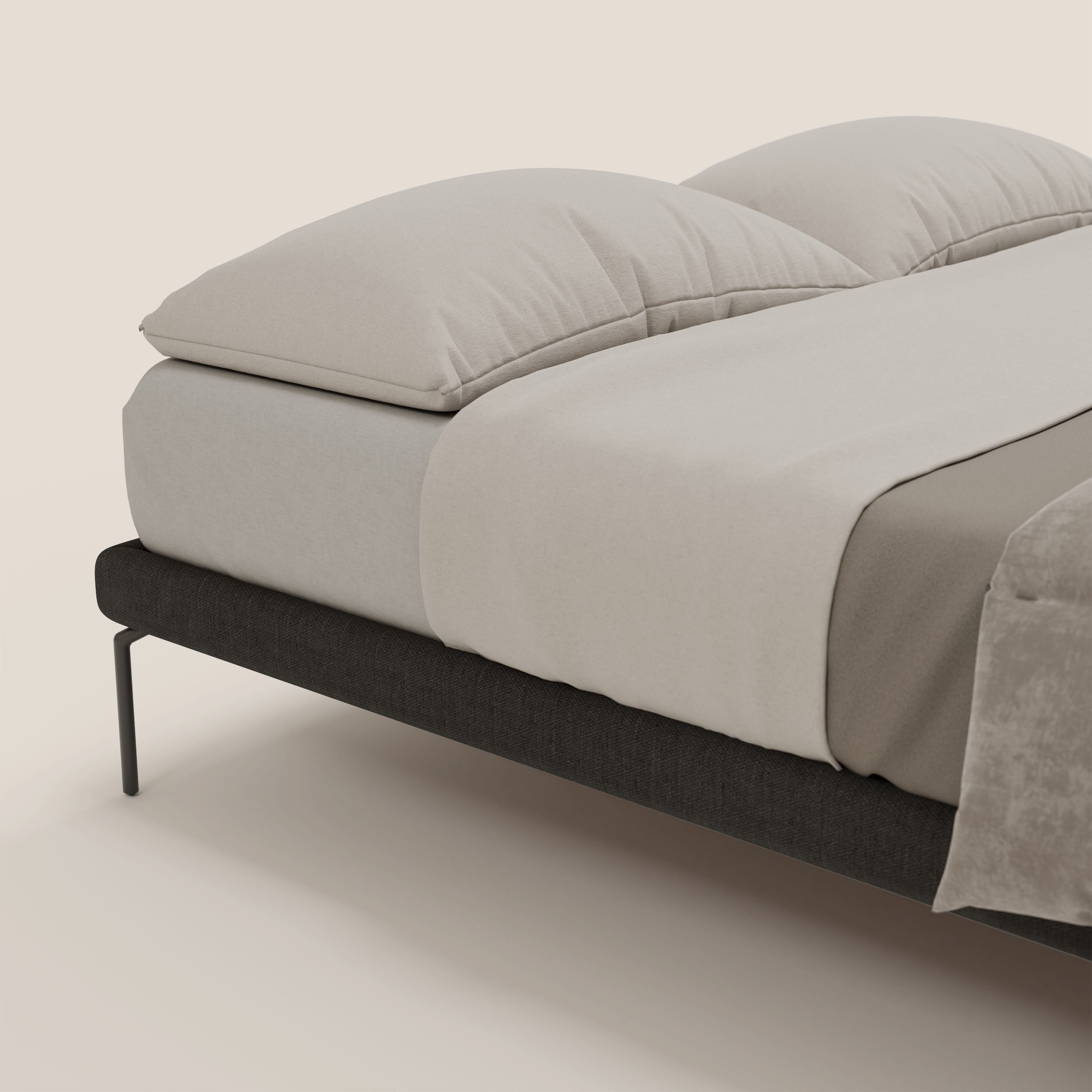 Un letto ben fatto è caratterizzato dal sommier sfoderabile Ring di Letti.store con gambe alte 24 cm in tessuto impermeabile T14 antracite, abbinato a grandi cuscini beige, lenzuola coordinate e coperta beige su fondo chiaro.
