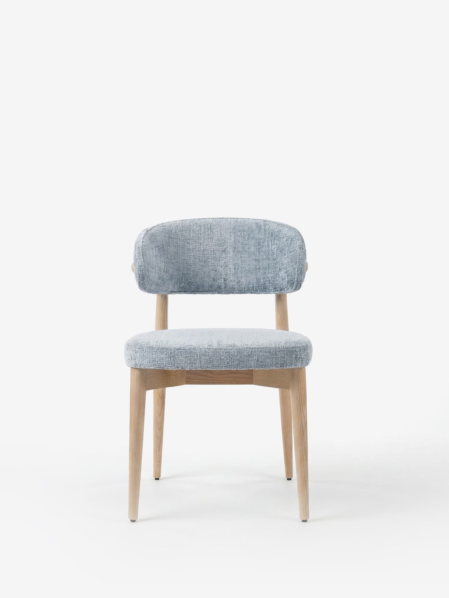 La sedia imbottita Dafne di Divani.Store presenta gambe e struttura in rovere naturale massiccio, uno schienale curvo e una seduta imbottita in ciniglia certificata OEKO-TEX® di colore azzurro, raffigurata su uno sfondo bianco a tinta unita per un look moderno.