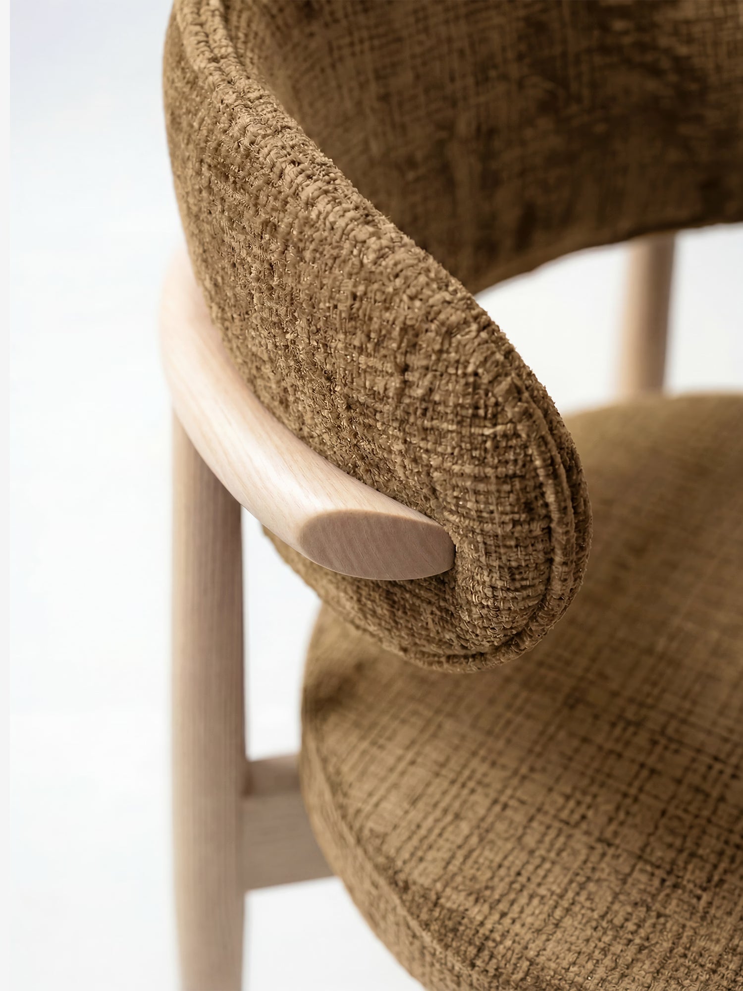 Primo piano della sedia imbottita “Dafne” di Divani.Store, realizzata in rovere massello naturale e ciniglia certificata OEKO-TEX®, caratterizzata da uno schienale curvo, bordi arrotondati e morbidi e un rivestimento marrone testurizzato che crea un contrasto con il legno chiaro.