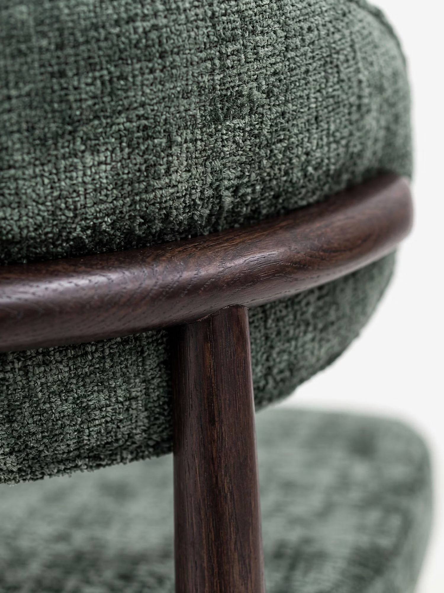 Primo piano della sedia di design imbottita Dafne di Divani.Store, realizzata con ciniglia certificata OEKO-TEX® in verde scuro e una struttura rotonda in legno massello wengé, che mette in risalto il tessuto testurizzato e la finitura liscia del legno massello.