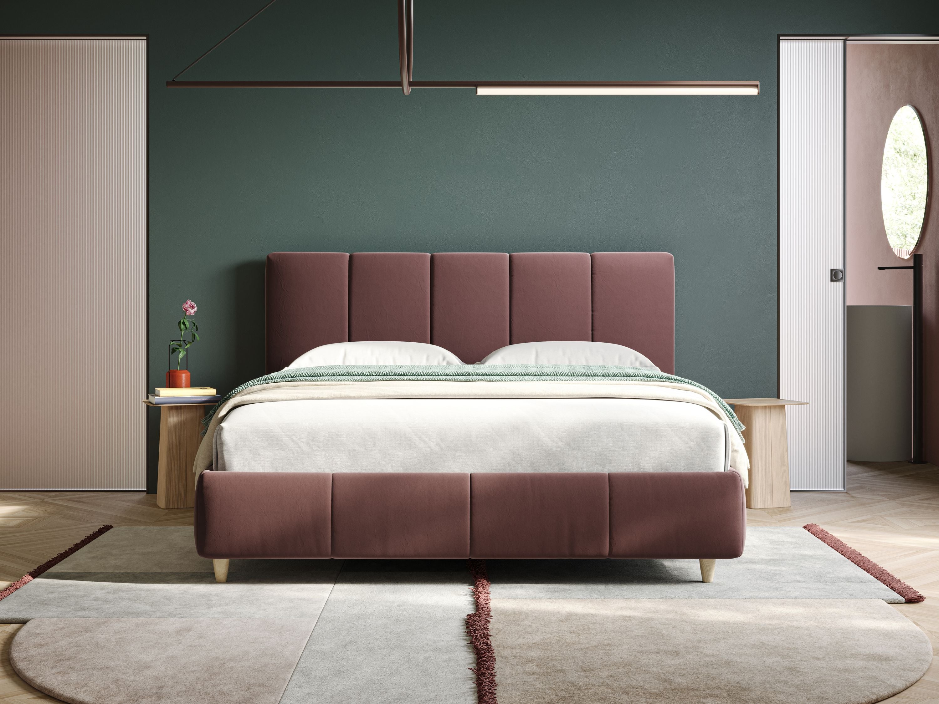 Una camera da letto moderna è caratterizzata dal letto Laura imbottito contenitore e sfoderabile in microfibra velluto impermeabile T09 salmone di Letti.store, dalla biancheria da letto chiara, dal comodino minimalista con un fiore rosa, dalla parete d'accento verde scuro, dalle porte scorrevoli beige e dal tappeto geometrico.