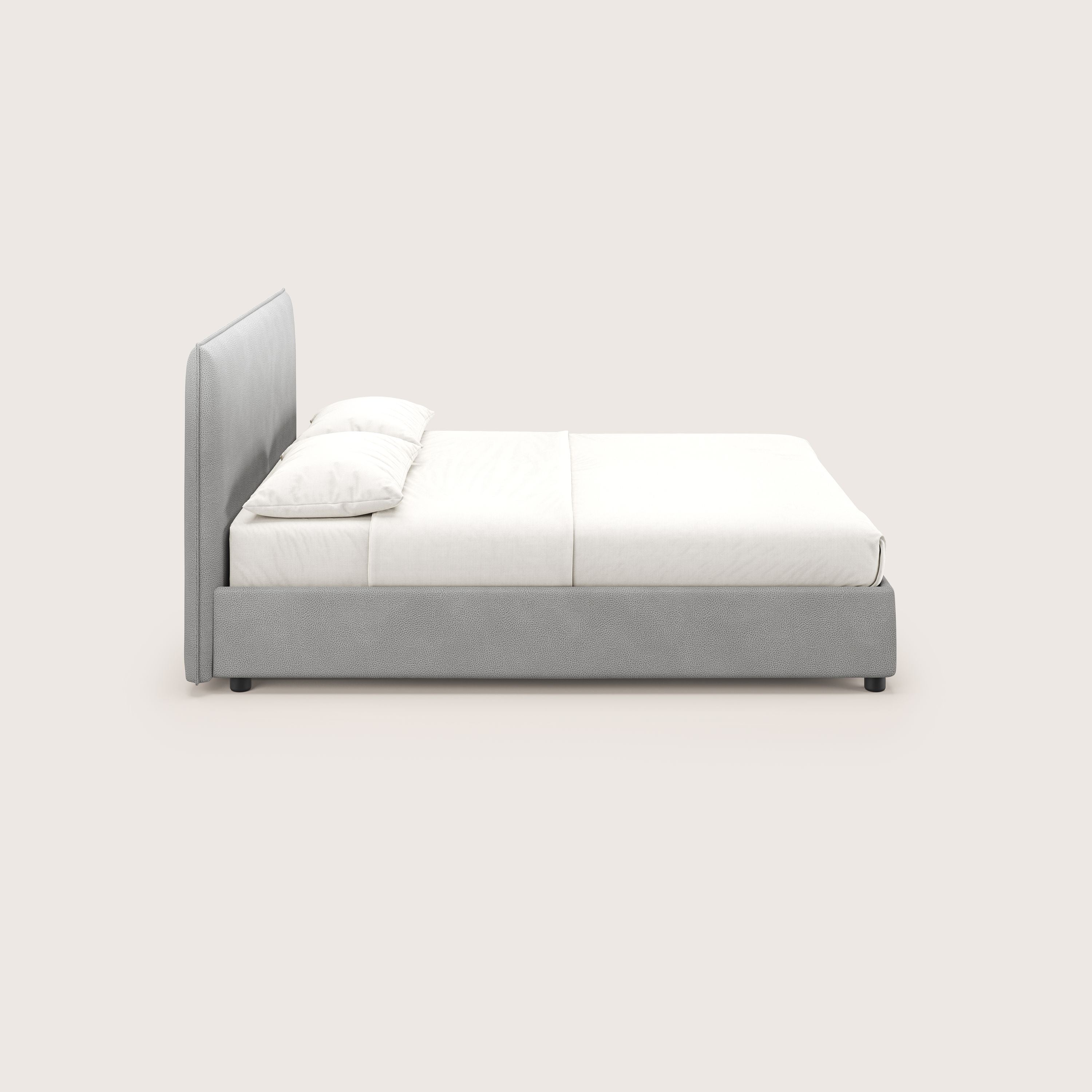 Vista laterale di Nina letto contenitore di Letti.store: un letto dal design minimal in microfibra grigia antimacchia effetto pelle, con struttura e testata imbottite, biancheria da letto bianca ed elegante stile italiano su sfondo chiaro.
