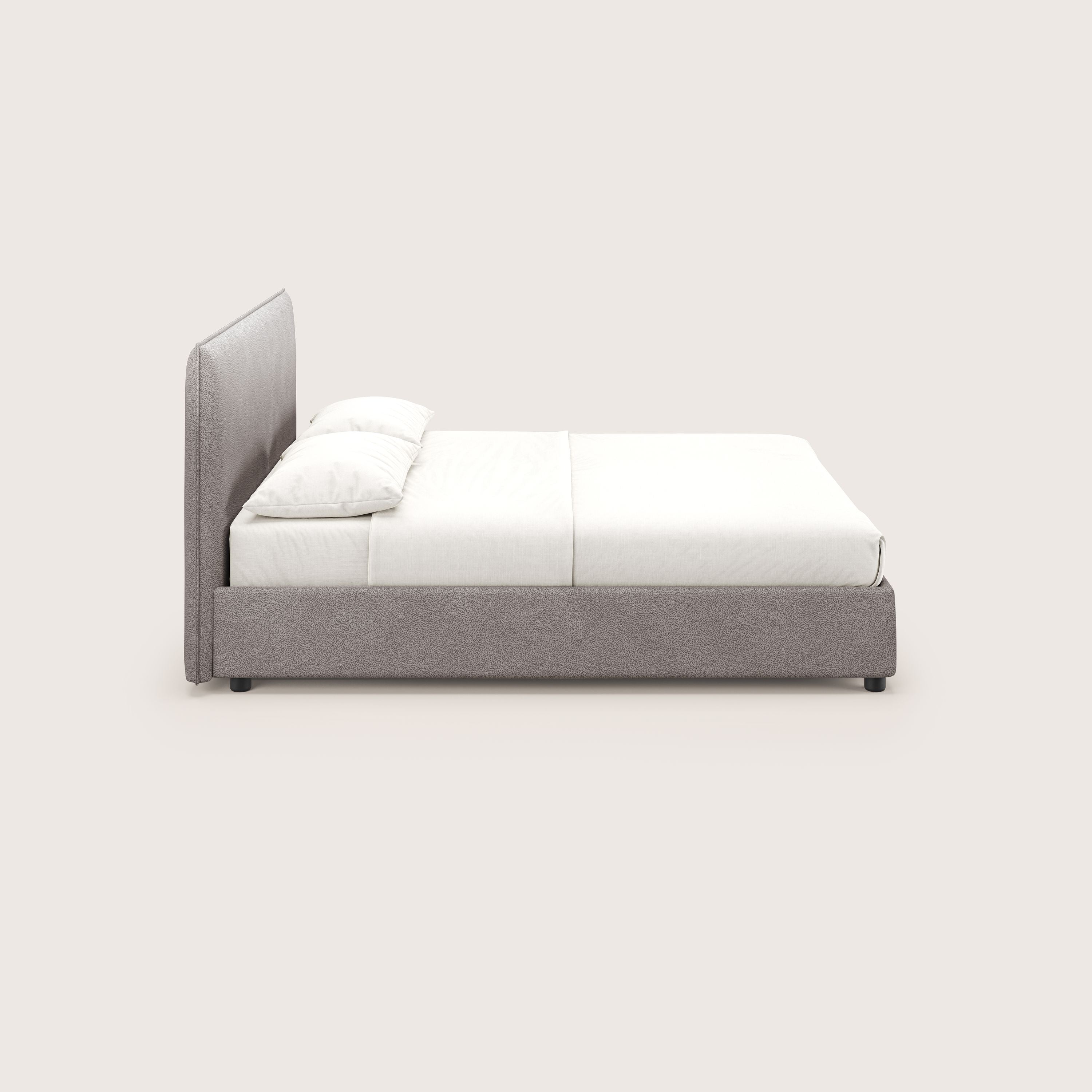 Vista laterale di Nina letto contenitore di Letti.store, un letto dal design minimale in microfibra antimacchia color tortora, con testata e struttura alte e imbottite, ordinatamente realizzato con lenzuola e cuscini bianchi su uno sfondo chiaro.