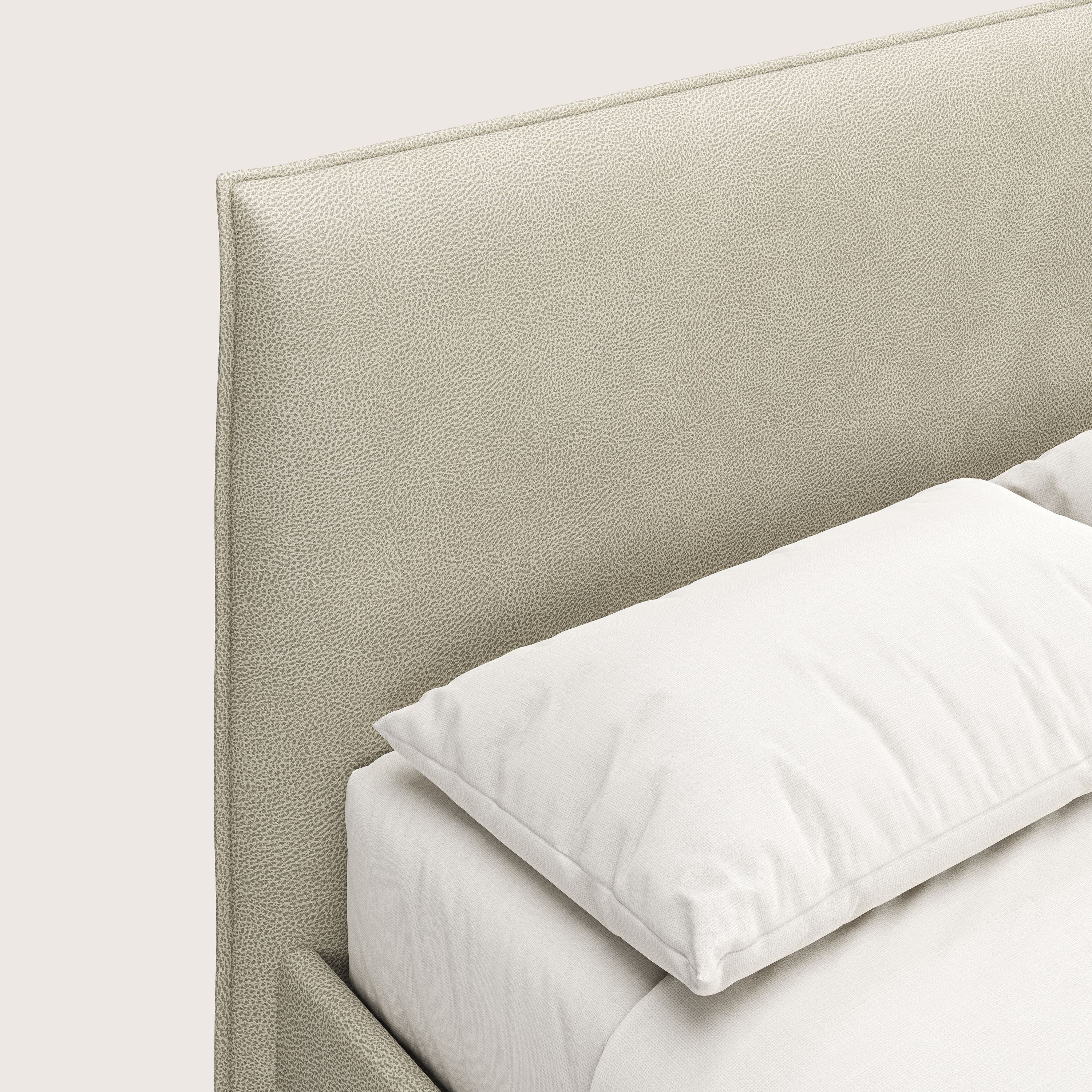 Un primo piano del letto contenitore Nina di Letti.store, caratterizzato da una testiera in microfibra effetto pelle panna chiaro e da un design minimalista che spicca sullo sfondo a tinta unita.