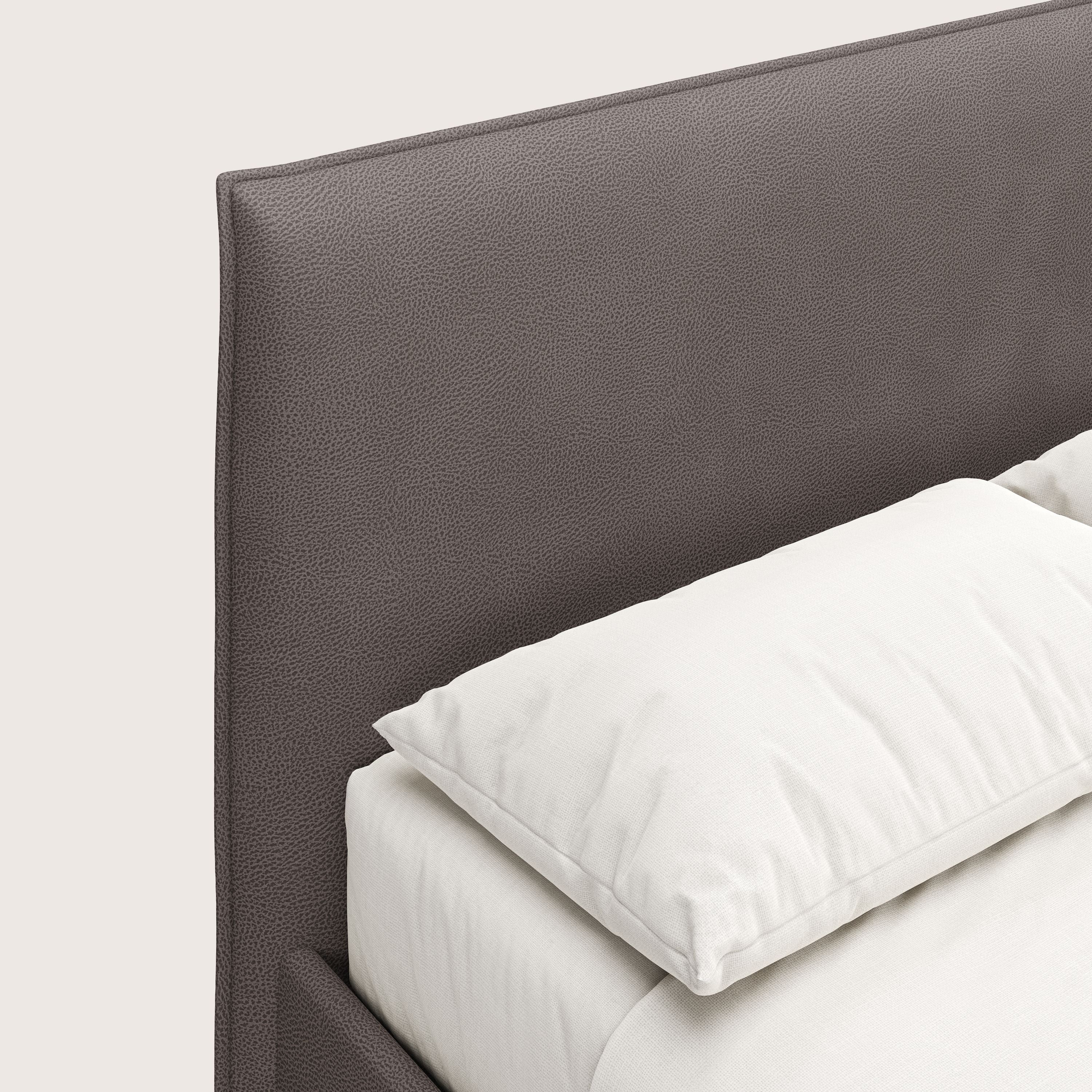 Primo piano del letto contenitore Nina di Letti.store, caratterizzato da un design minimale in microfibra marrone facile da pulire. La biancheria da letto bianca evidenzia il suo raffinato stile italiano su uno sfondo chiaro.