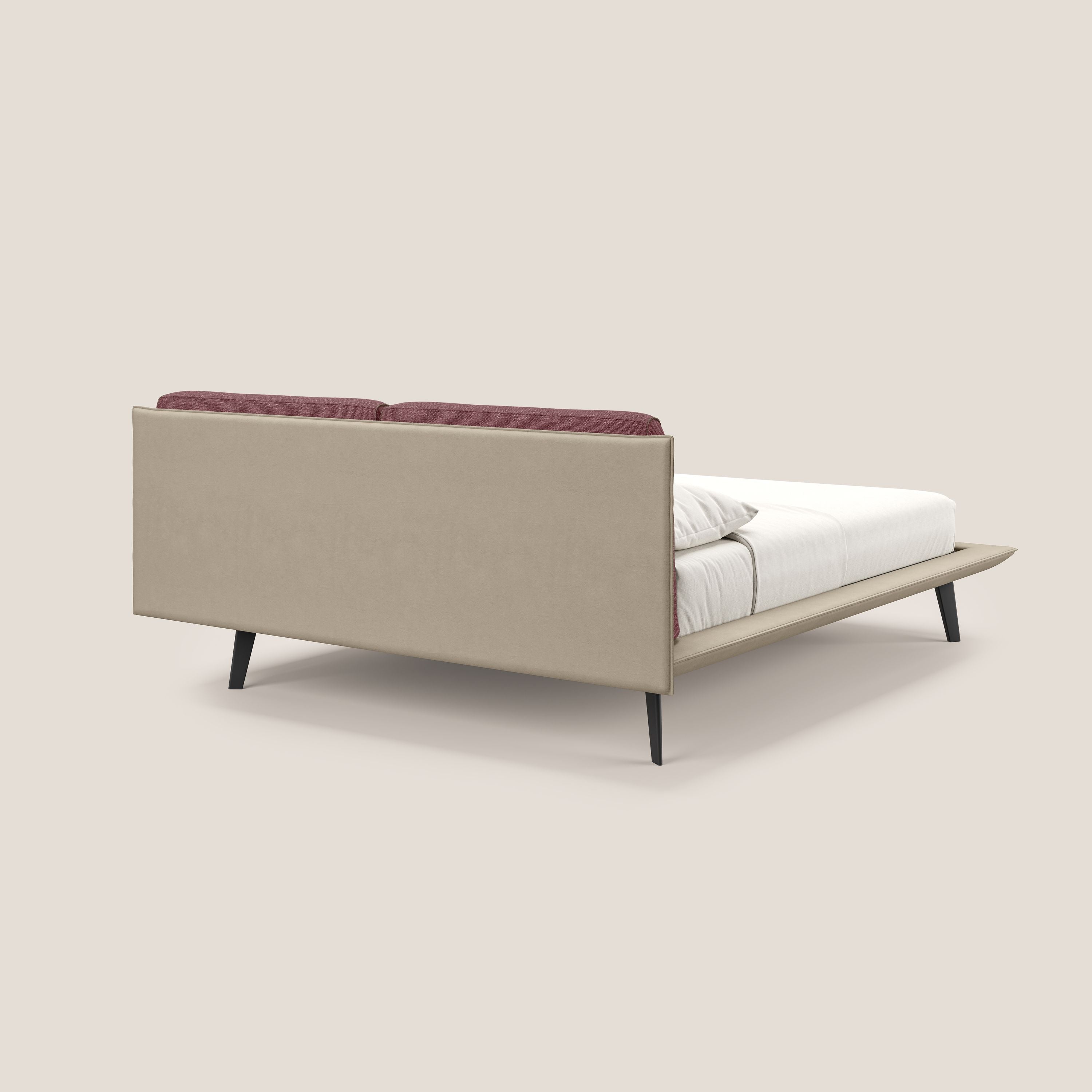 Il letto di design Petra di Letti.store è caratterizzato da una struttura imbottita in tortora-rosso bicolore impermeabile T11 e T06, cuscini in piuma e gambe in mogano. Presentato con biancheria da letto bianca su sfondo beige chiaro.