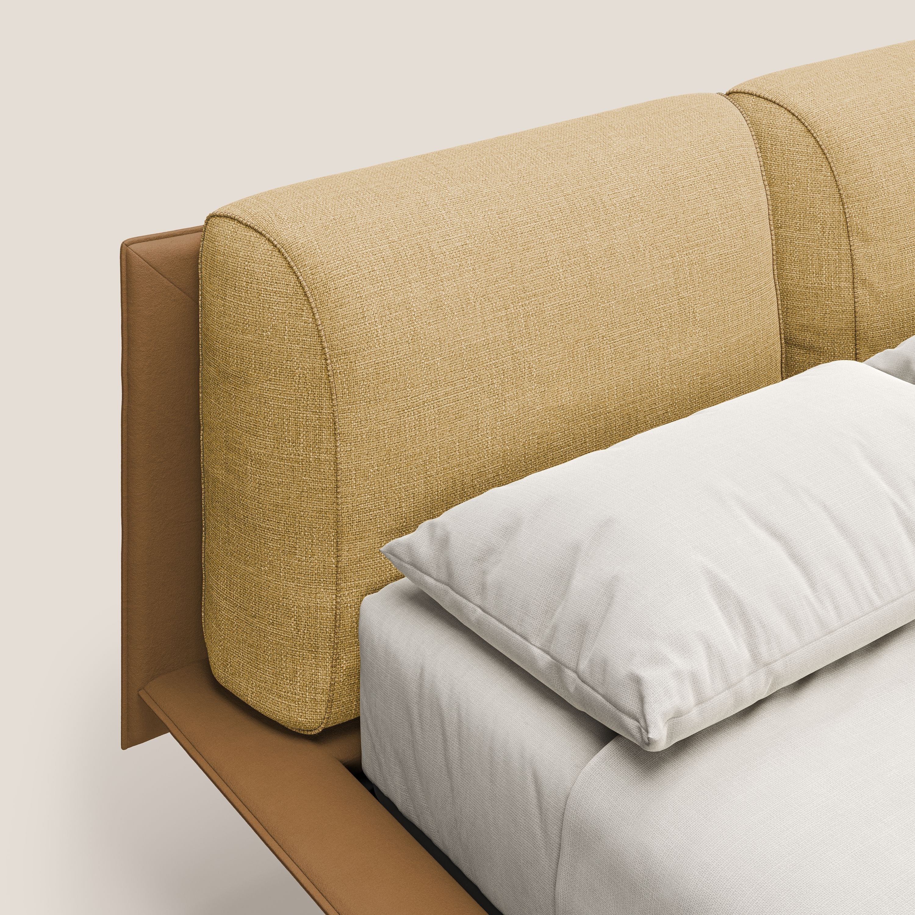 Primo piano di Petra letto di design bicolore di Letti.store, con tessuto impermeabile T11 e T06 in cuoio-giallo, cuscini in piuma e piedi in mogano. Un cuscino bianco e un lenzuolo grigio poggiano sul materasso su uno sfondo beige.