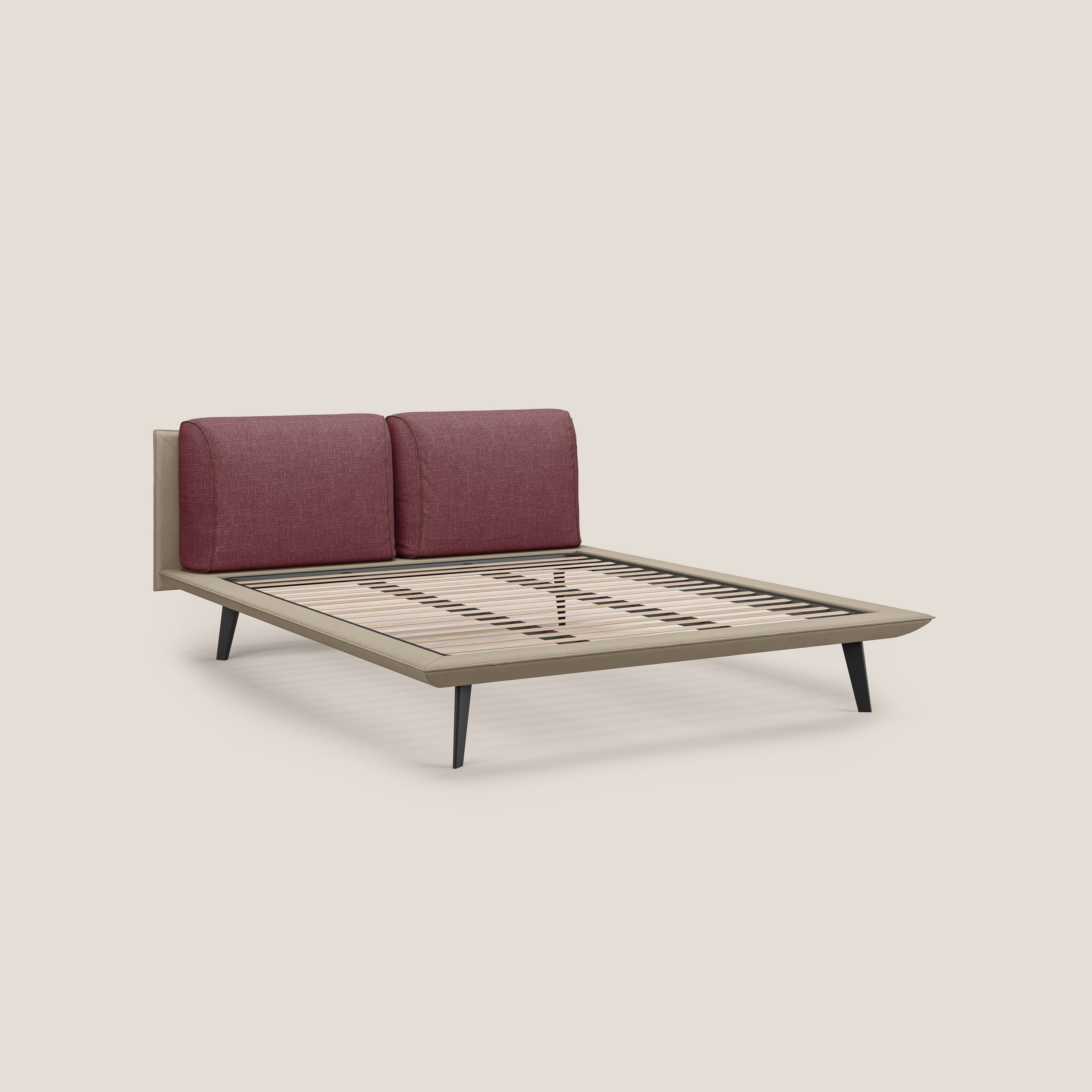 Il letto di design Petra di Letti.store è caratterizzato dal tessuto impermeabile bicolore T11 e T06 (tortora - rosso), dai cuscini in piuma, dalla testata imbottita, dalla rete ortopedica a doghe in legno chiaro e dai piedi angolati in mogano. Su fondo tinta unita beige.