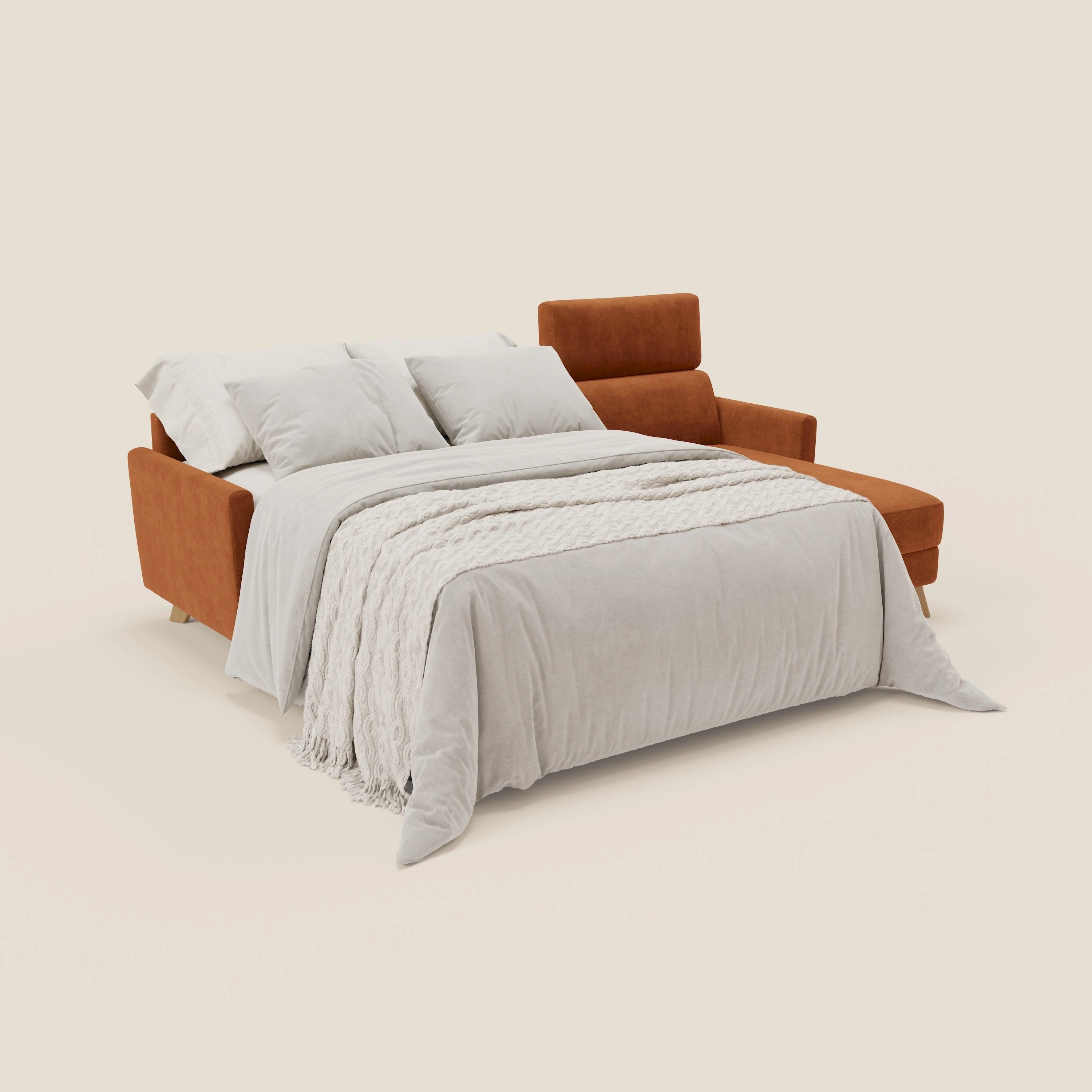 Il divano letto angolare sfoderabile Francy di Divani.Store, in tessuto smacchiabile T17 arancio con chaise contenitore e poggiatesta reclinabili, è presentato come letto con lenzuola beige chiaro e coperta crema su sfondo bianco sporco.