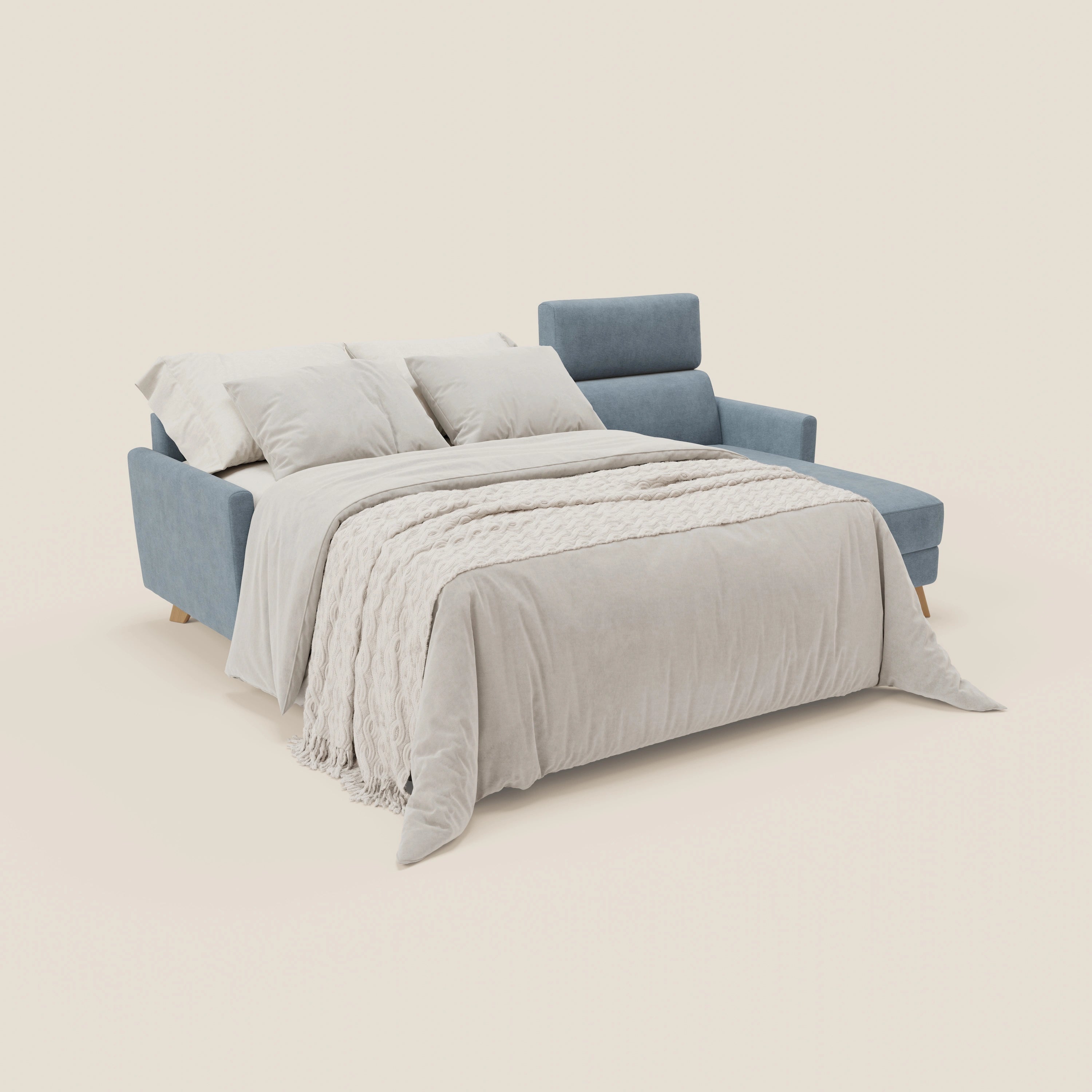 Il divano letto angolare Francy sfoderabile di Divani.Store, in tessuto smacchiabile T17 carta da zucchero, con penisola contenitore e poggiatesta reclinabili, è mostrato aperto a letto con biancheria beige e tre cuscini su sfondo chiaro.