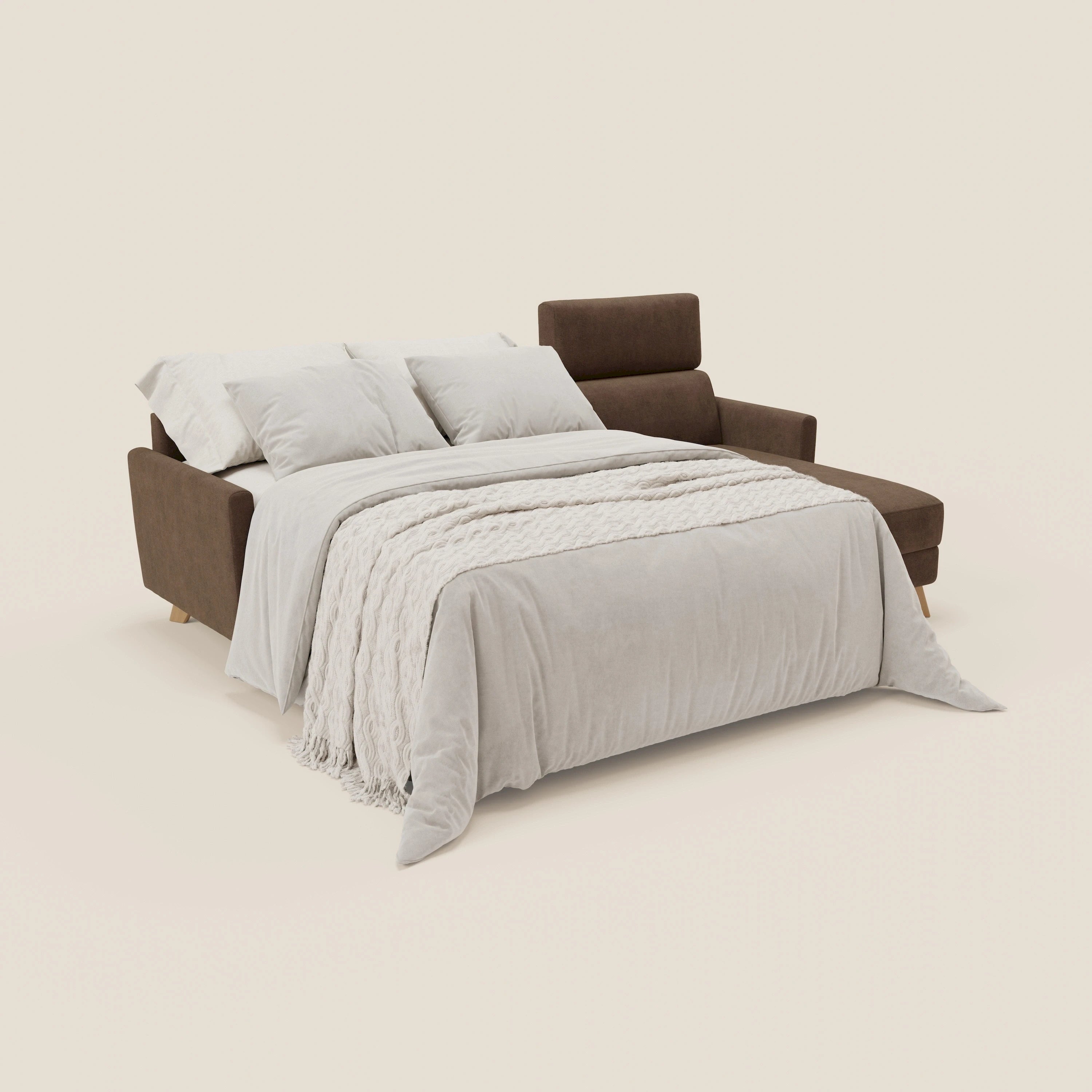 Un divano letto angolare sfoderabile Francy di Divani.Store in T17 marrone è mostrato dispiegato come un letto, vestito con biancheria grigia chiara e una coperta strutturata, con poggiatesta reclinabili e chaise contenitore incorporato su uno sfondo crema.