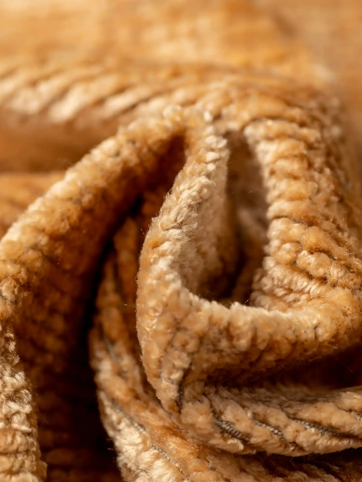 Un primo piano del bouclé marrone-dorato con trama in rilievo, S02 ELITE materico strutturato e smacchiabile dall’effetto ciniglia, caratterizzato da pieghe profonde e morbide, da un pelo soffice e da ricche nervature.
