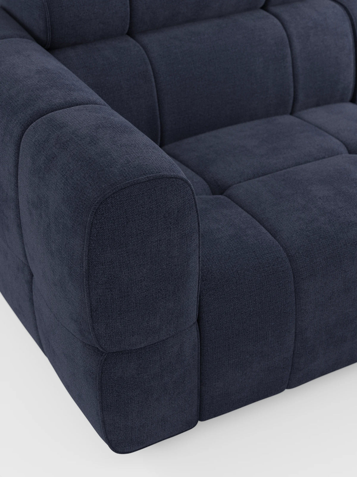 Un primo piano del divano modulare Giotto a 4 posti con poggiatesta reclinabili e funzione relax elettrica opzionale, rivestito in tessuto smacchiabile T23, caratterizzato da un tessuto testurizzato blu scuro, braccioli arrotondati e cuscini profondi con trapuntatura quadrata su sfondo bianco.