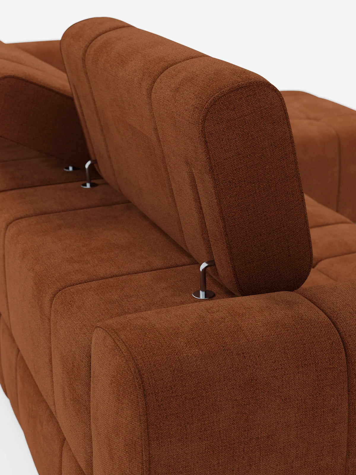 Un primo piano di un divano angolare modulare Giotto color ruggine a 5 posti, lungo 296 cm, con penisola e funzione relax elettrica opzionale, rivestito in tessuto smacchiabile T23, con schienali regolabili su supporti argentati su uno sfondo bianco a tinta unita.