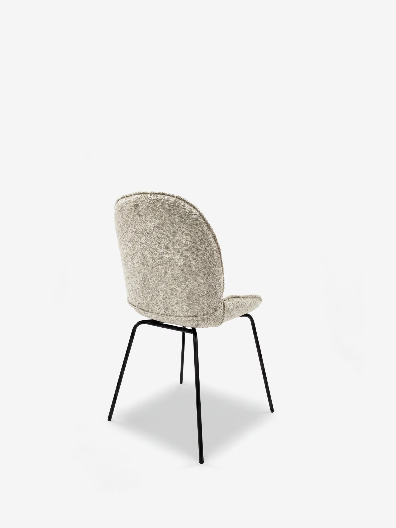 La sedia imbottita Iride di Divani.Store presenta uno schienale e una seduta arrotondati, rivestiti in tessuto grigio chiaro con trama in rilievo, e slanciate gambe angolate in metallo nero. Ripresa dal lato posteriore sinistro su uno sfondo bianco, questa elegante sedia in stile contemporaneo coniuga stile e comfort.
