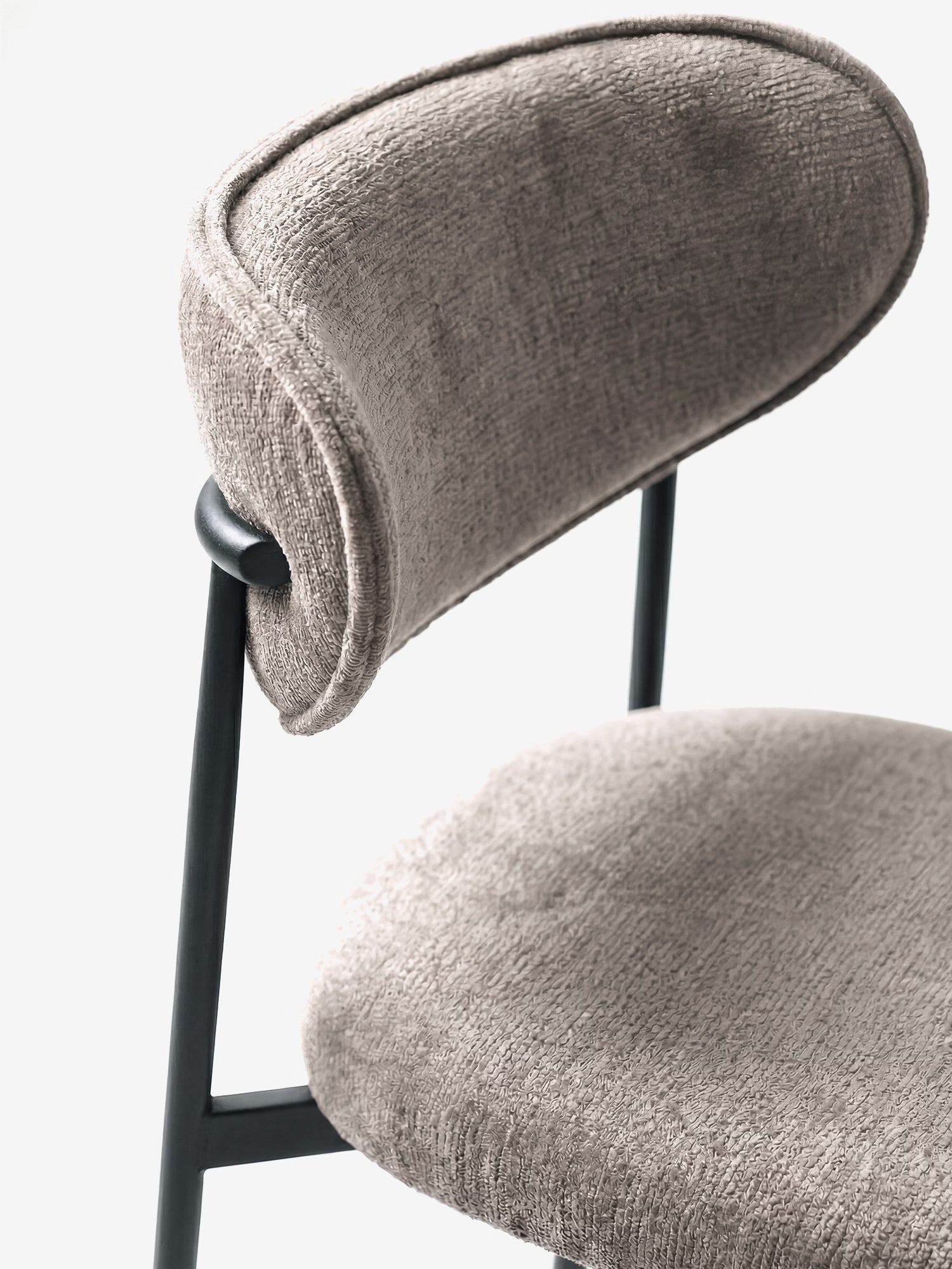 Primo piano della sedia Luce, imbottita in morbida ciniglia, di Divani.Store, caratterizzata da una seduta beige chiaro con trama in rilievo, uno schienale arrotondato e una struttura minimalista in metallo nero. Solo una parte della sedia è visibile su uno sfondo bianco.
