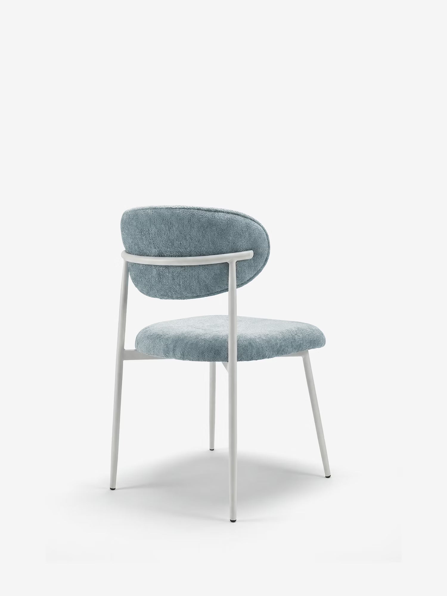 La sedia Luce di Divani.Store presenta un design contemporaneo con struttura in metallo verniciato a polvere bianco, schienale imbottito e curvo e seduta imbottita in morbido tessuto azzurro. Le sue linee minimaliste e pulite e le gambe slanciate sono visibili in una vista posteriore angolata.