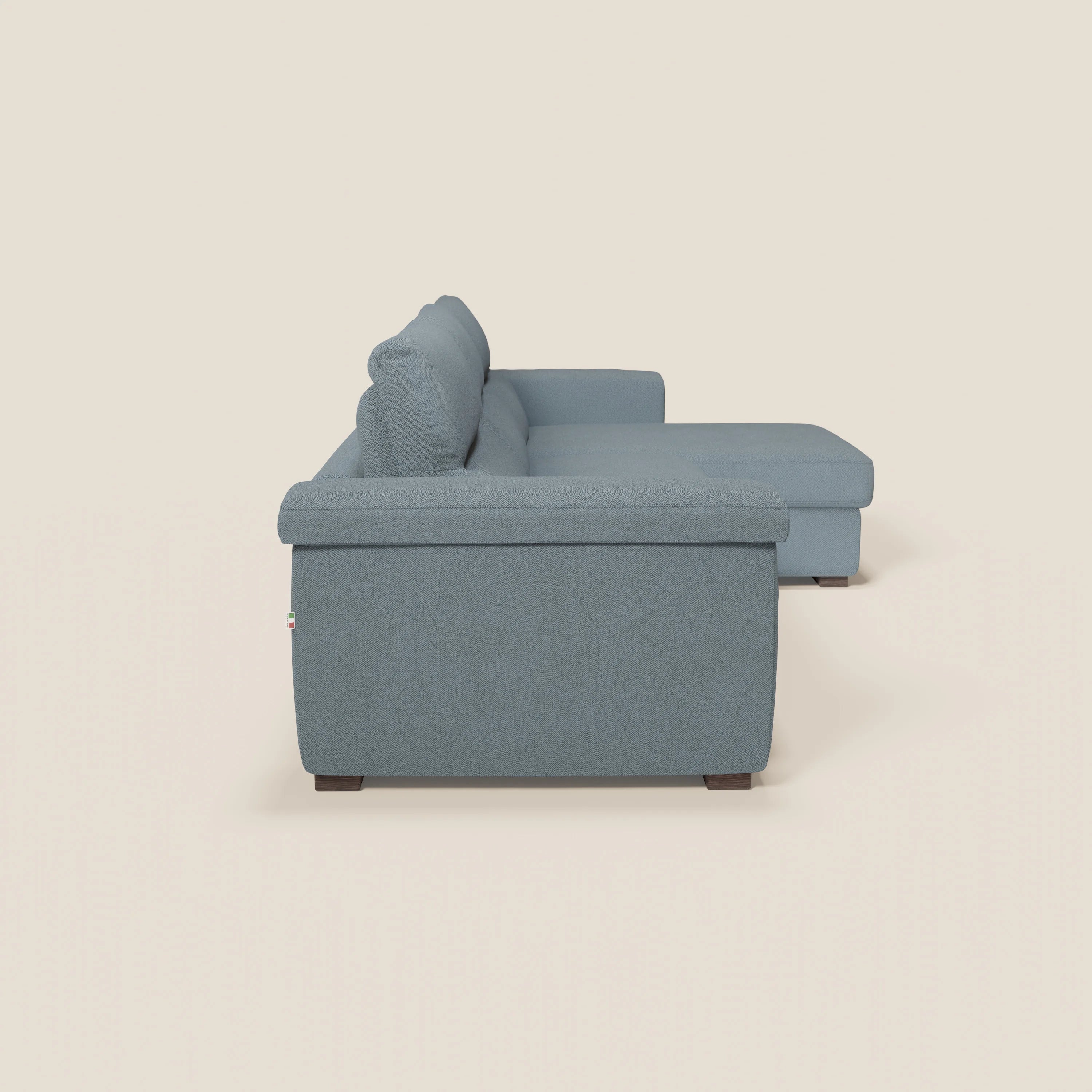Il divano letto angolare Magnolia con penisola contenitore di Divani.Store, presentato in tessuto T05 carta da zucchero azzurro, è caratterizzato da una chaise longue destra, cuscini Comfort Profondo, ampi braccioli e gambe corte in legno scuro su uno sfondo bianco sporco.