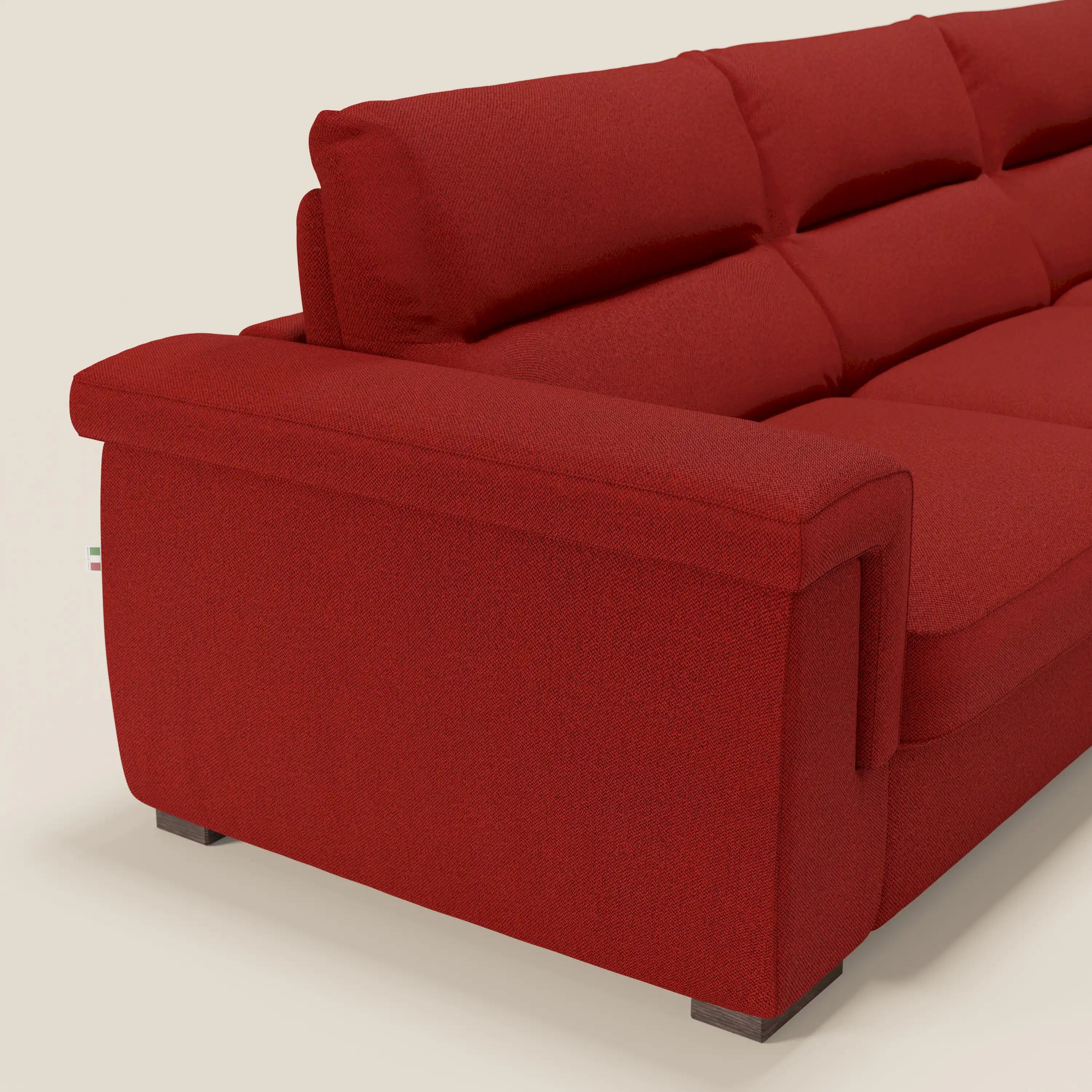 Il divano letto angolare Magnolia con penisola contenitore di Divani.Store, in tessuto smacchiabile T05 rosso e materasso H18 cm, è mostrato su piedi scuri contro uno sfondo neutro, evidenziando linee pulite e praticità nascosta.