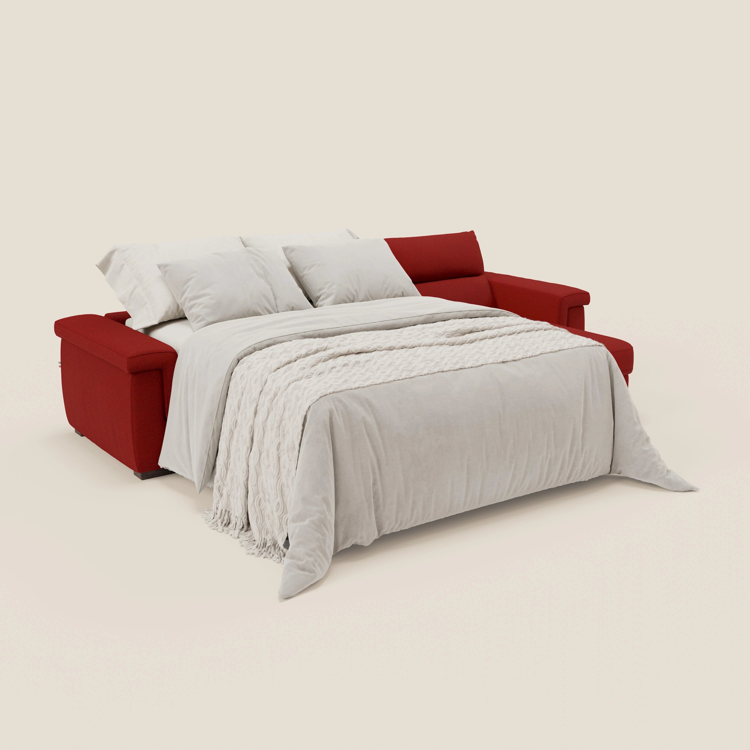 Il divano letto angolare Magnolia con Penisola Contenitore di Divani.Store, in tessuto smacchiabile rosso T05 e materasso H18 cm, è aperto a letto con biancheria bianca, evidenziando la praticità nascosta e il comfort elegante del prodotto.
