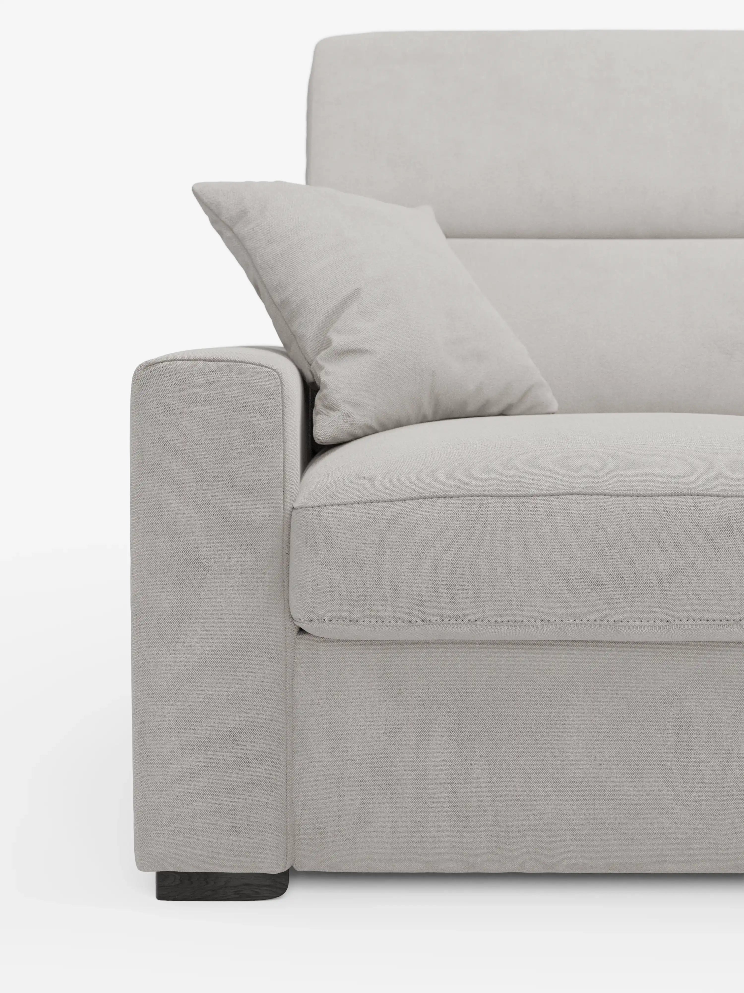 Primo piano del divano letto Maximus a 3 posti con materasso ALTO 20 cm di Divani.Store, rivestito in grigio chiaro, con particolare attenzione al bracciolo sinistro, al cuscino di seduta e al cuscino decorativo abbinato appoggiato allo schienale. Questo divano letto è dotato di poggiatesta reclinabili e tessuto antimacchia certificato Oeko-Tex, poggia su gambe corte in legno scuro e si distingue su uno sfondo bianco a tinta unita.