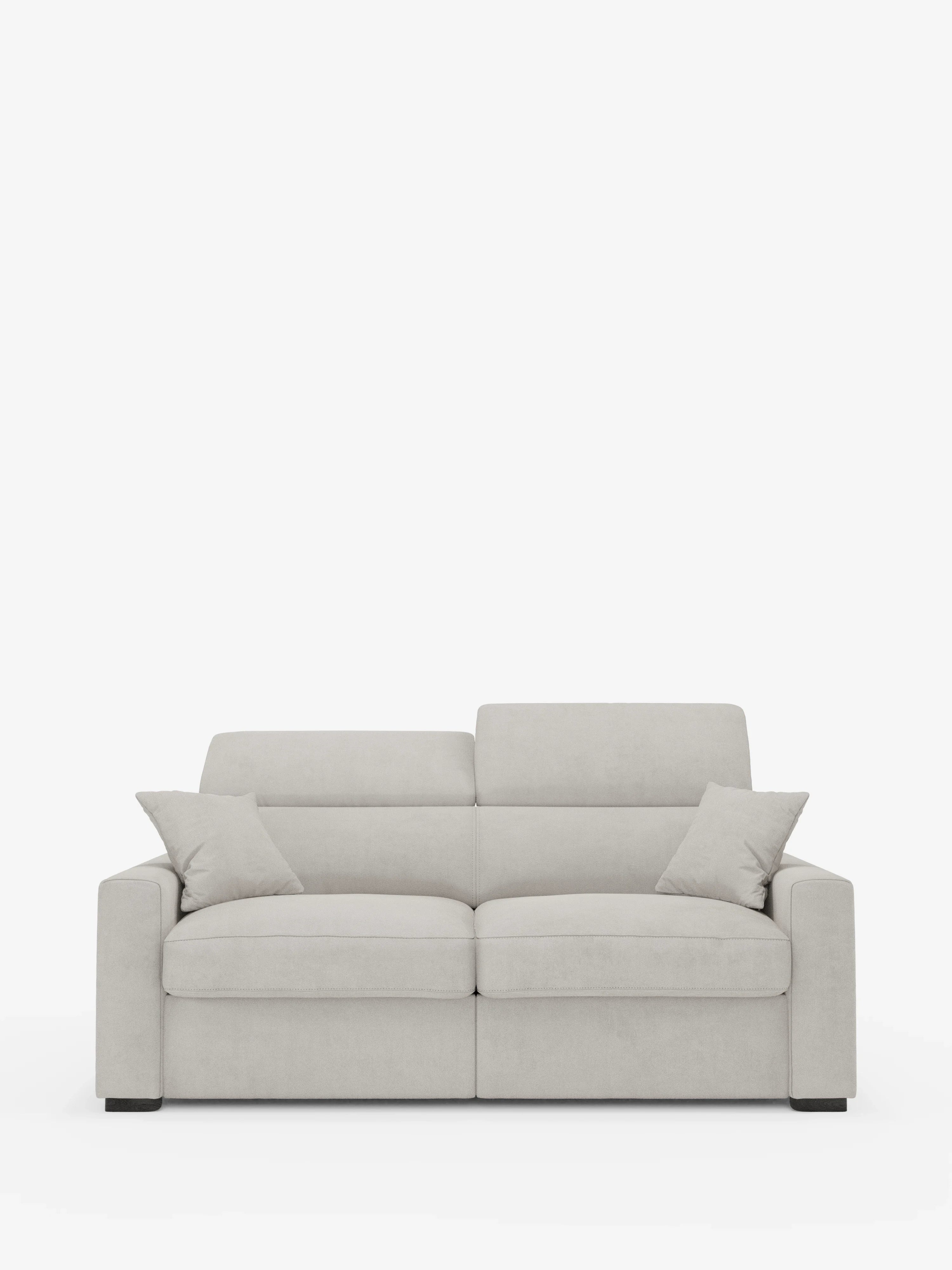Un divano a tre posti moderno, di colore grigio chiaro — il Maximus Divano letto di Divani.Store — presenta ampi braccioli, due cuscini dello schienale abbinati e due cuscini decorativi angolari. Simile a un elegante divano letto matrimoniale, è posizionato su uno sfondo bianco a tinta unita e si distingue per le linee pulite, i piedini quadrati neri e i poggiatesta reclinabili. Il divano include inoltre un materasso extra-spesso da 20 cm ed è rivestito in tessuto Oeko-Tex resistente alle macchie.