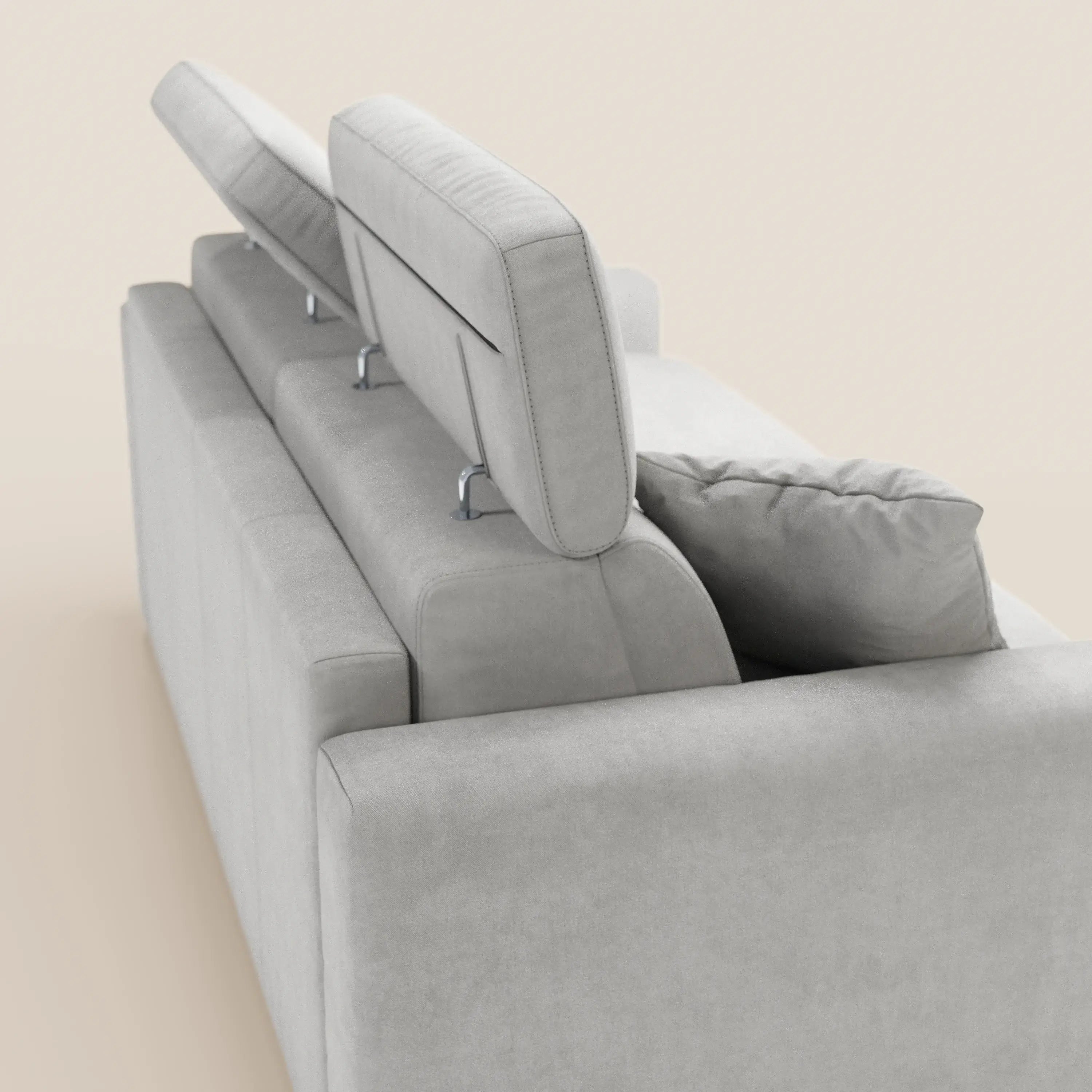 Il divano letto Maximus a 3 posti con materasso ALTO 20 cm di Divani.Store è presentato in tessuto grigio chiaro con certificazione Oeko-Tex e rivestimento antimacchia. Vista posteriore: un poggiatesta regolabile in posizione sollevata, uno parzialmente sollevato e uno abbassato. Uno cuscino coordinato è appoggiato sullo schienale; sfondo semplice e neutro.