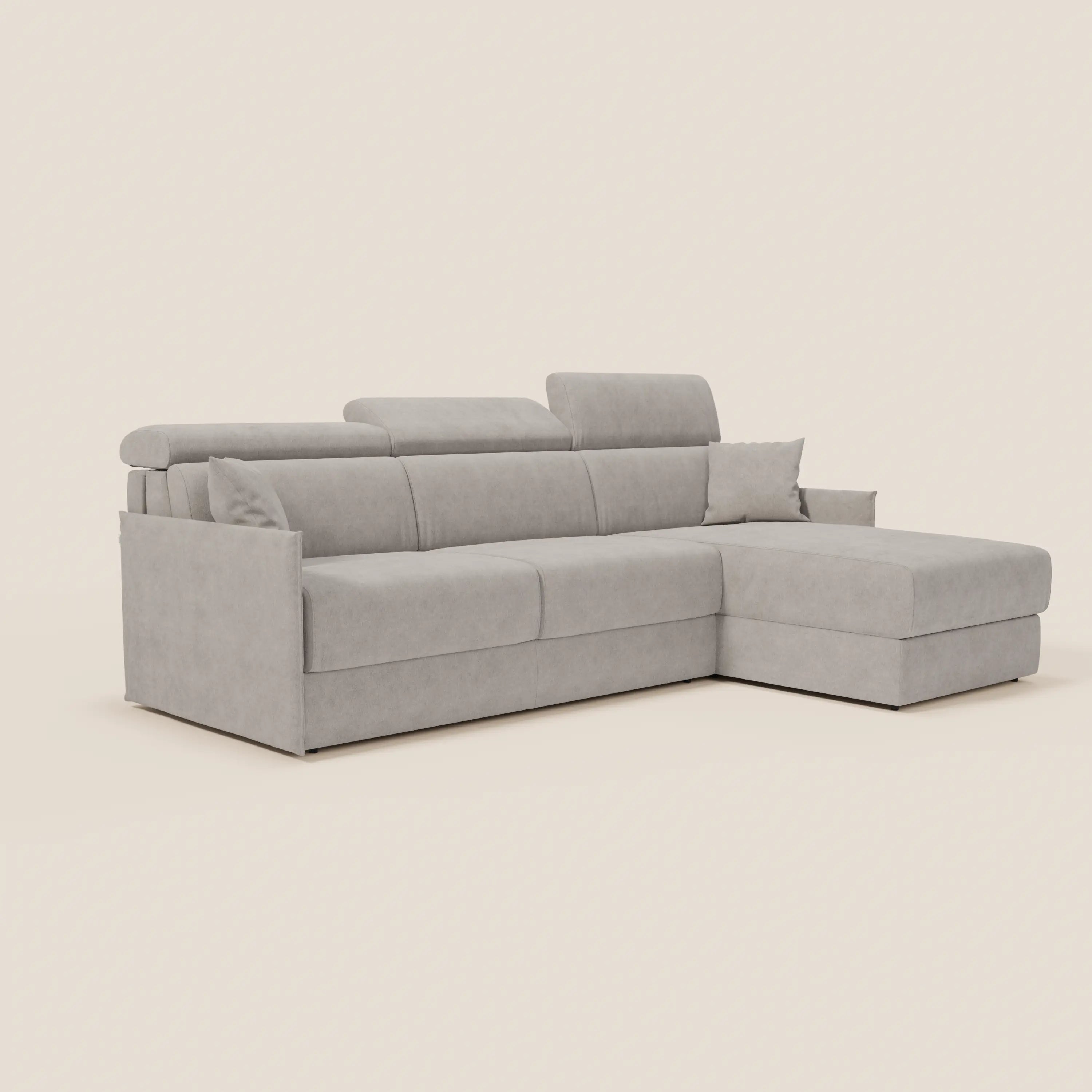 Il divano letto angolare compatto Miryam di Divani.Store è un moderno divano a 3 posti grigio chiaro con chaise longue orientata a destra, dotato di poggiatesta reclinabili, ampi braccioli, due cuscini e tessuto T31 antimacchia.