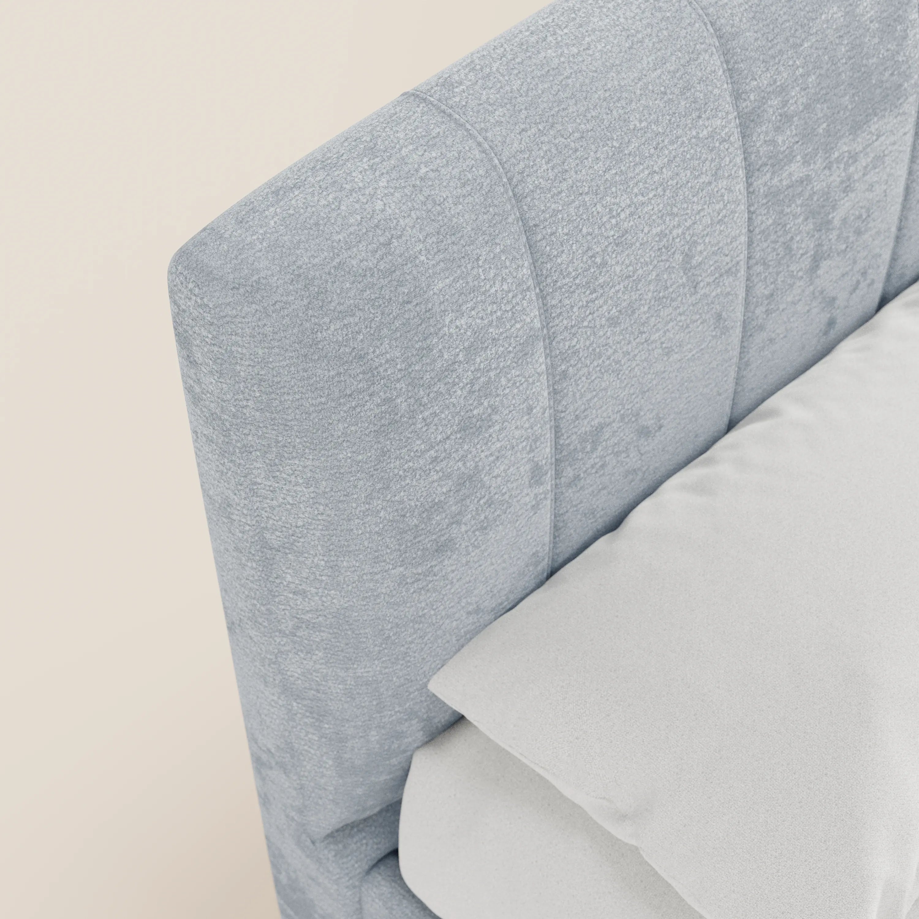 Primo piano del letto imbottito ONYX con contenitore di Letti.store, caratterizzato da una testiera in tessuto azzurro certificato Oeko-Tex® con cuciture verticali. Il letto in stile moderno è rivestito con biancheria da letto bianca, che risalta su uno sfondo beige chiaro a tinta unita.