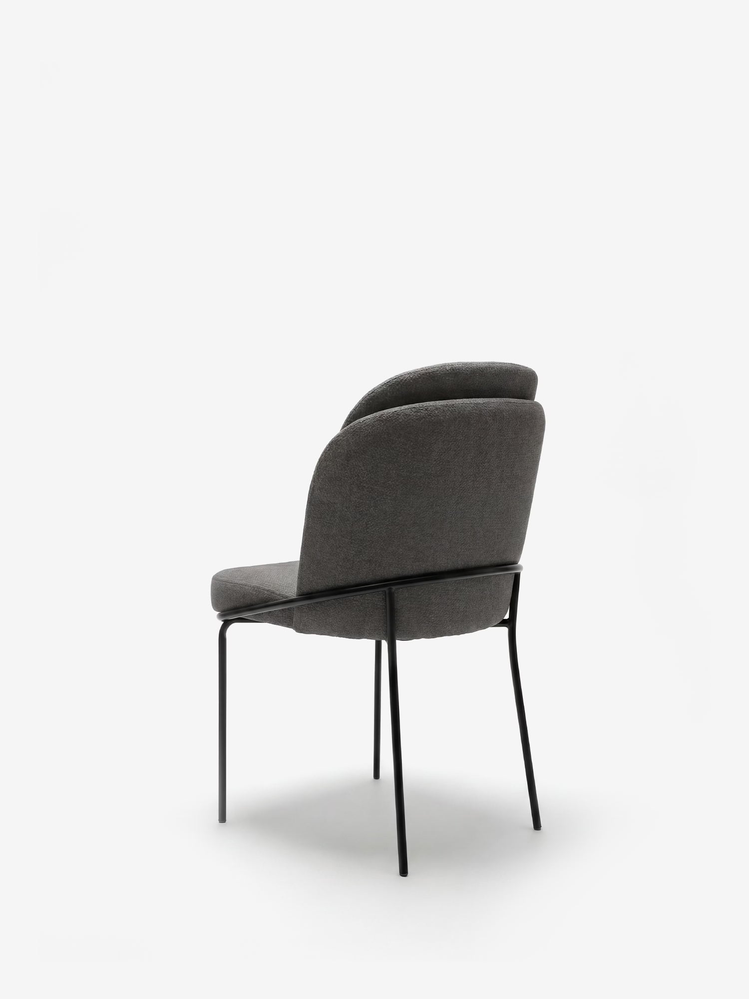 La sedia imbottita Plissè in tessuto impermeabile di Divani.Store presenta uno schienale plissettato e sottili gambe in metallo nero. Questa sedia moderna è raffigurata leggermente inclinata verso sinistra su uno sfondo bianco a tinta unita.