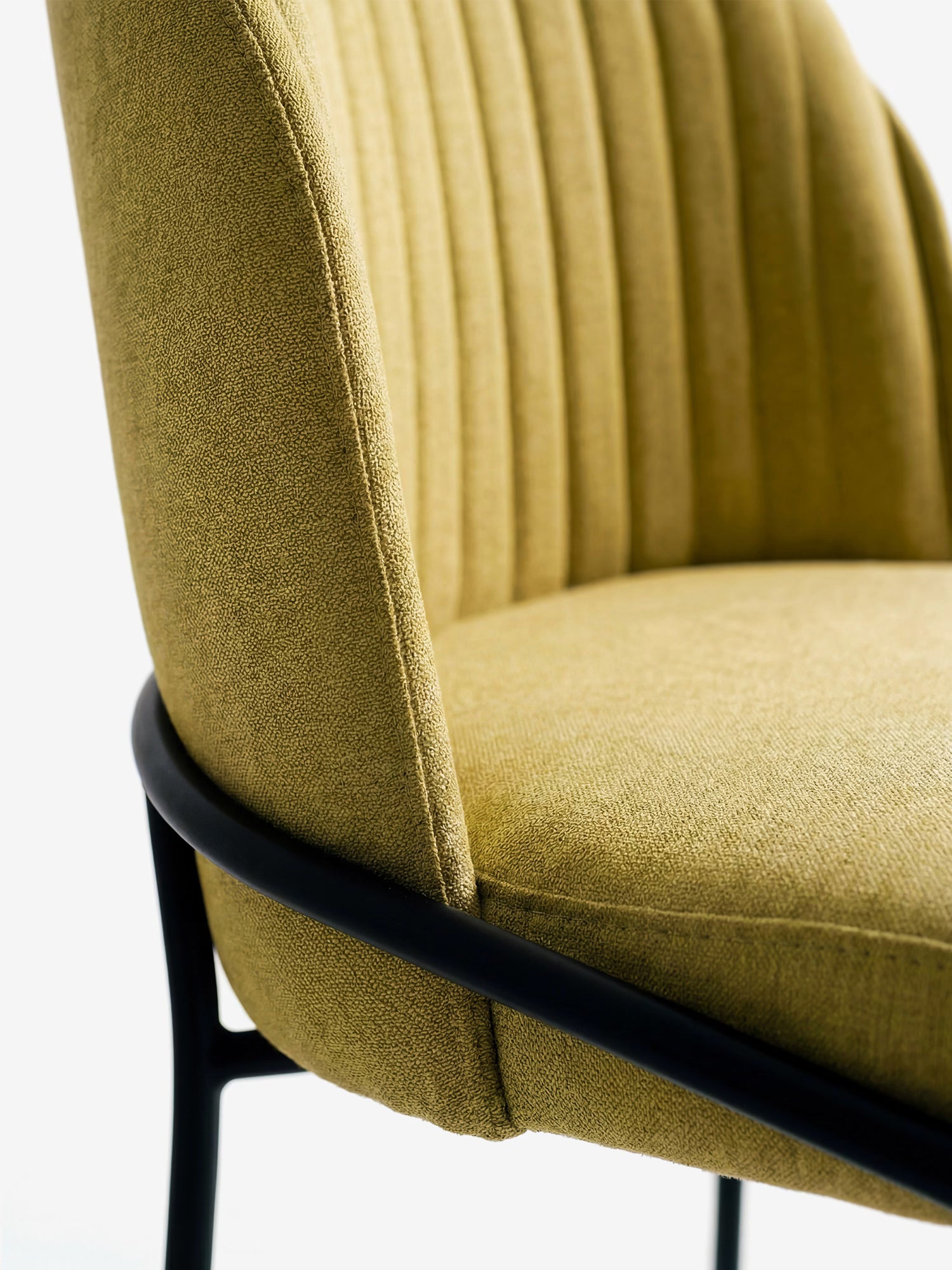 Primo piano su Plissè, la sedia imbottita di Divani.Store, caratterizzata da un tessuto impermeabile giallo senape, schienale plissettato e gambe in metallo nero, per un look moderno su sfondo bianco.