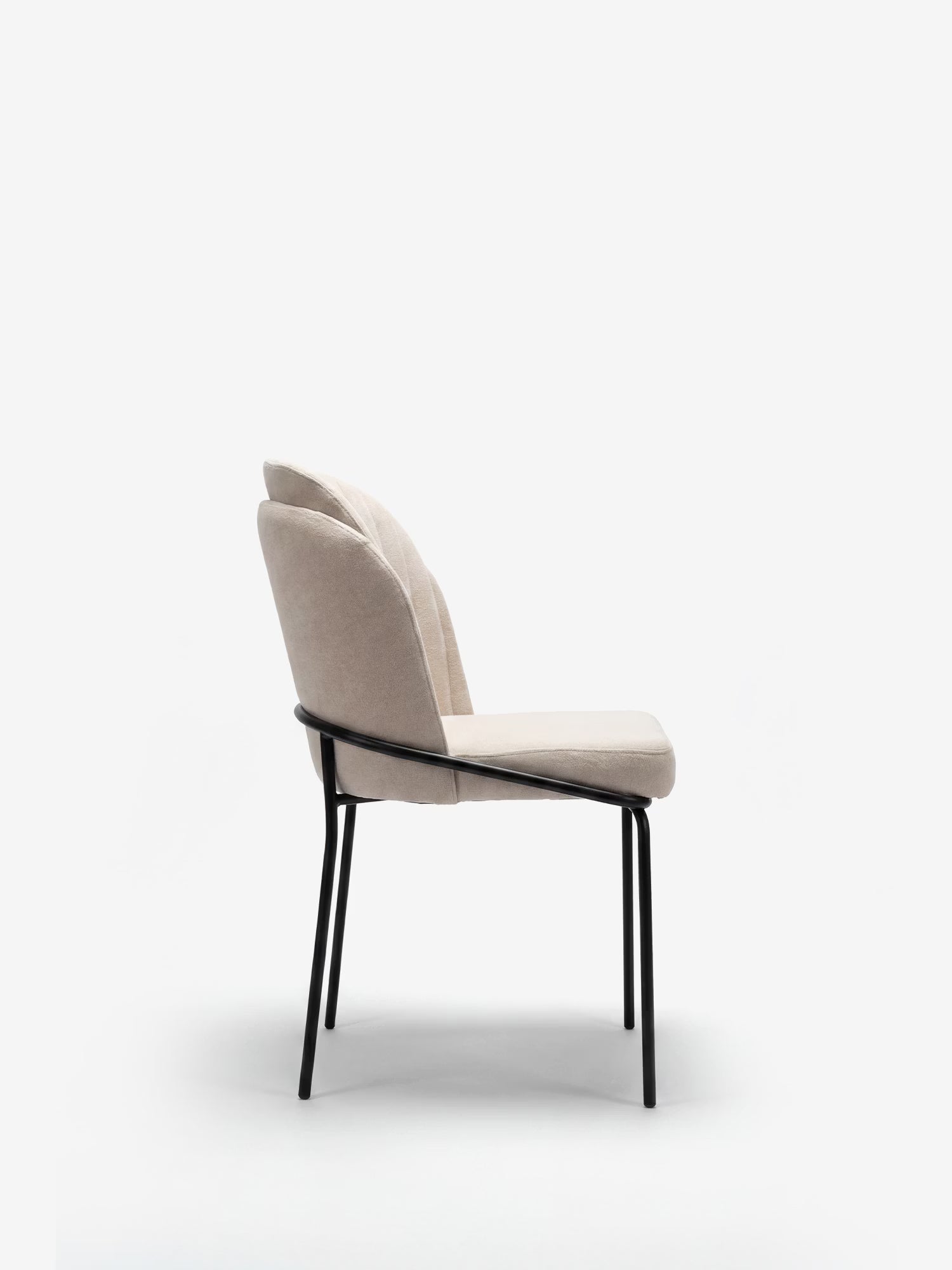 La sedia imbottita Plissè di Divani.Store presenta seduta e schienale in tessuto beige plissettato impermeabile, con sottili gambe in metallo nero, ritratte di profilo su uno sfondo bianco per un effetto elegante e minimalista.