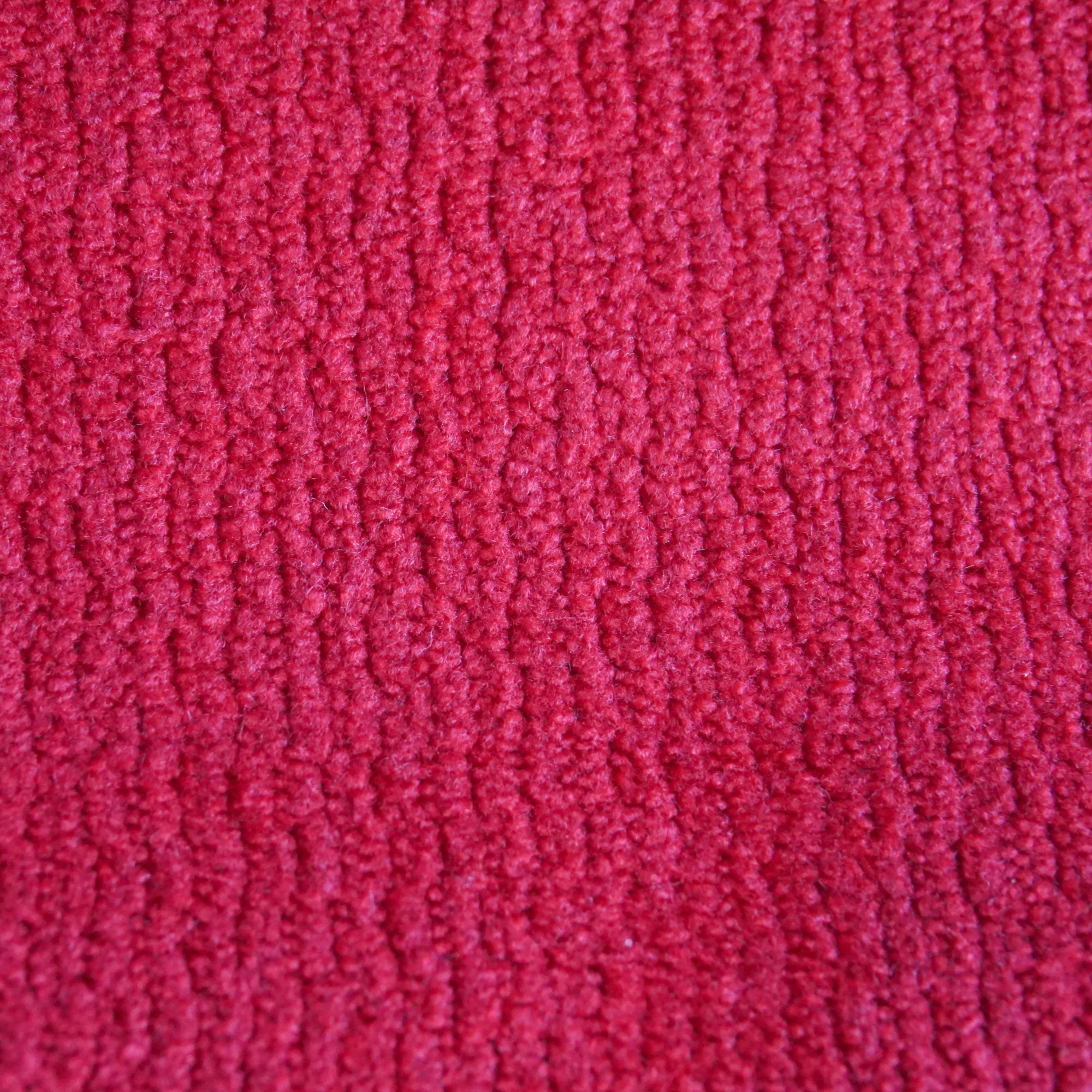 Primo piano di Personalizzazione in T32 di Divani.Store: un tessuto rosso vibrante caratterizzato da una texture morbida e vaporosa con un motivo a coste ondulate ripetute, perfetto per rivestimenti o abbigliamento.