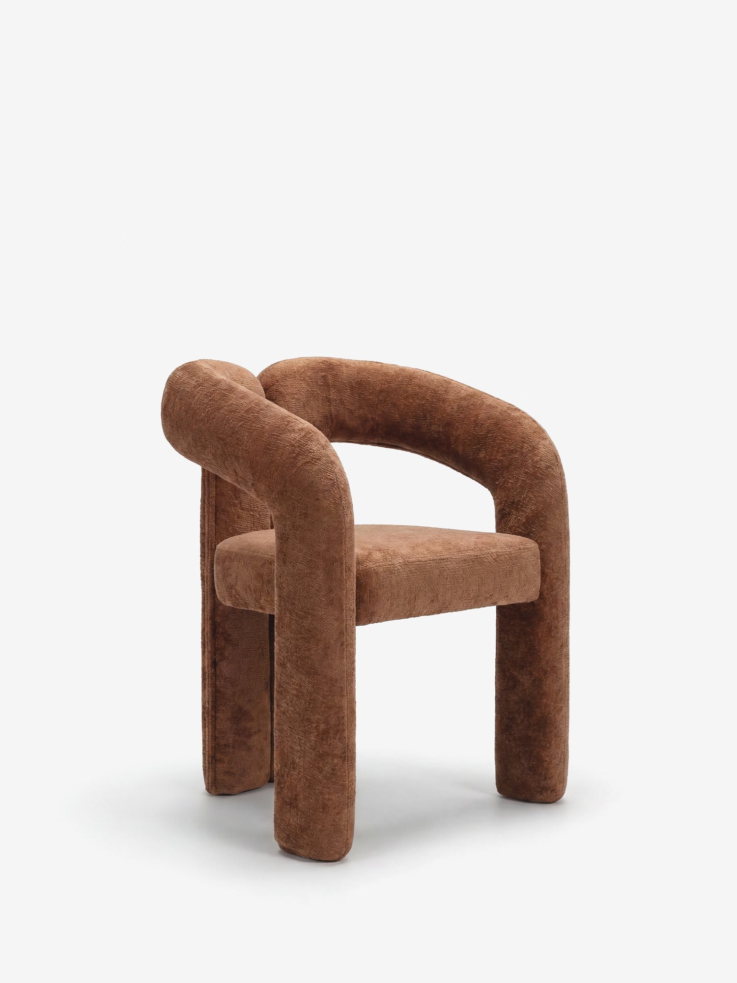 La sedia di design Sibilla di Divani.Store si caratterizza per un look minimalista e scultoreo, con un lussuoso rivestimento marrone, gambe spesse e arrotondate e uno schienale arcuato, il tutto interamente rivestito in morbido tessuto. Perfetta per gli spazi contemporanei, qui raffigurata su uno sfondo bianco a tinta unita.