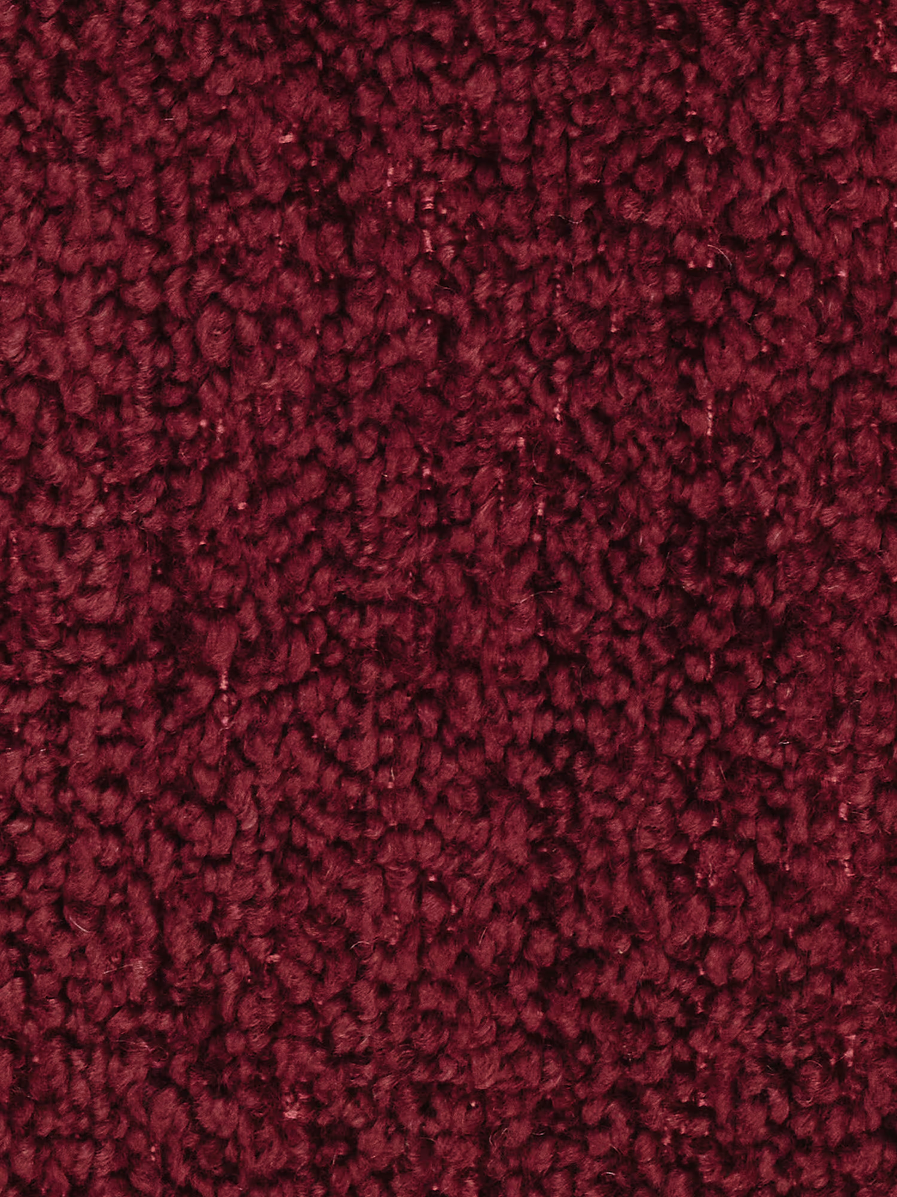Primo piano di un tappeto dalla trama rigata, di colore rosso intenso o bordeaux, con pelo ad anelli, perfetto per abbinarsi a un divano moderno. La superficie presenta fibre ben fitte e leggermente lucide, che gli conferiscono un aspetto soffice e morbido. Il colore è ricco e uniforme in tutta l'immagine, rendendolo uno sfondo ideale per un elegante divano componibile.