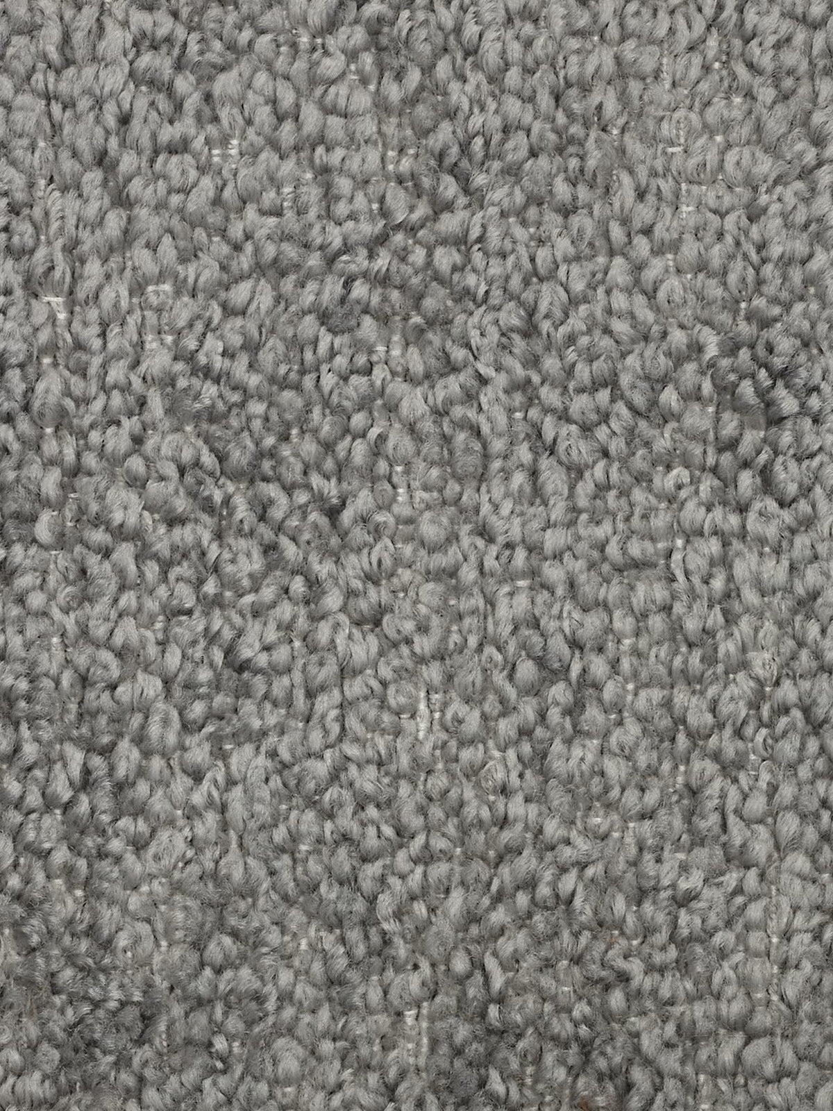 Primo piano di un tappeto grigio a pelo riccio con trama in rilievo. Le fibre formano piccoli anelli arrotondati, creando una superficie densa e morbida: una base ideale per qualsiasi divano modulare. Le varie sfumature di grigio aggiungono profondità e varietà, mettendo in risalto il motivo a trama fitta e l’aspetto soffice del tappeto, che si abbina perfettamente a un divano moderno negli spazi abitativi contemporanei.