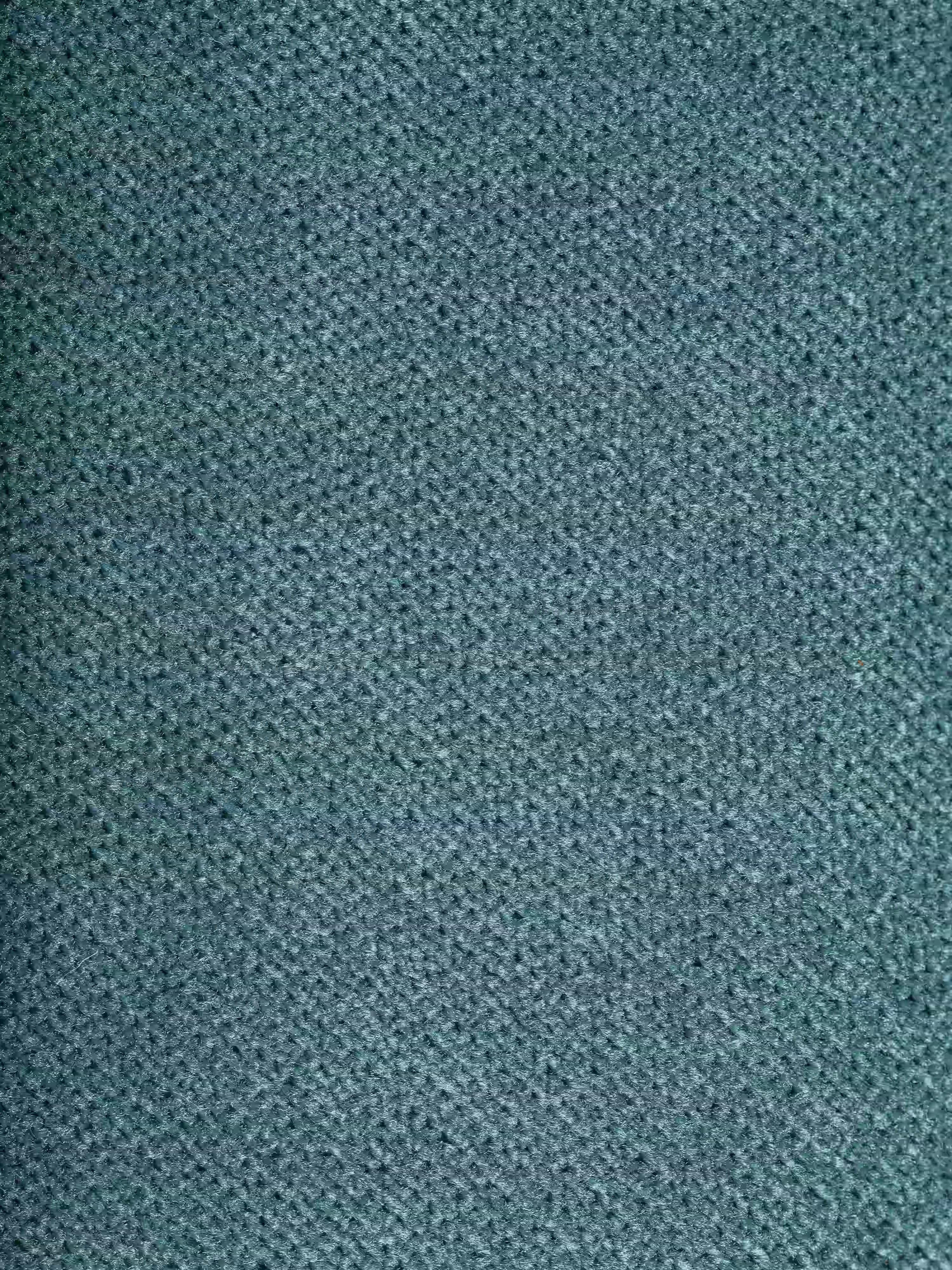 Primo piano del raffinato tessuto T30 dall’effetto vellutato, in una tenue tonalità blu-verde, presente sul divano angolare Michelangelo con penisola e sedute estensibili di Divani.Store. Il motivo intessuto, fitto e leggermente in rilievo, conferisce al tessuto un aspetto delicatamente strutturato e piacevole al tatto. L'immagine è inquadrata in modo stretto per mettere in risalto esclusivamente il tessuto, senza altri oggetti o sfondi visibili.