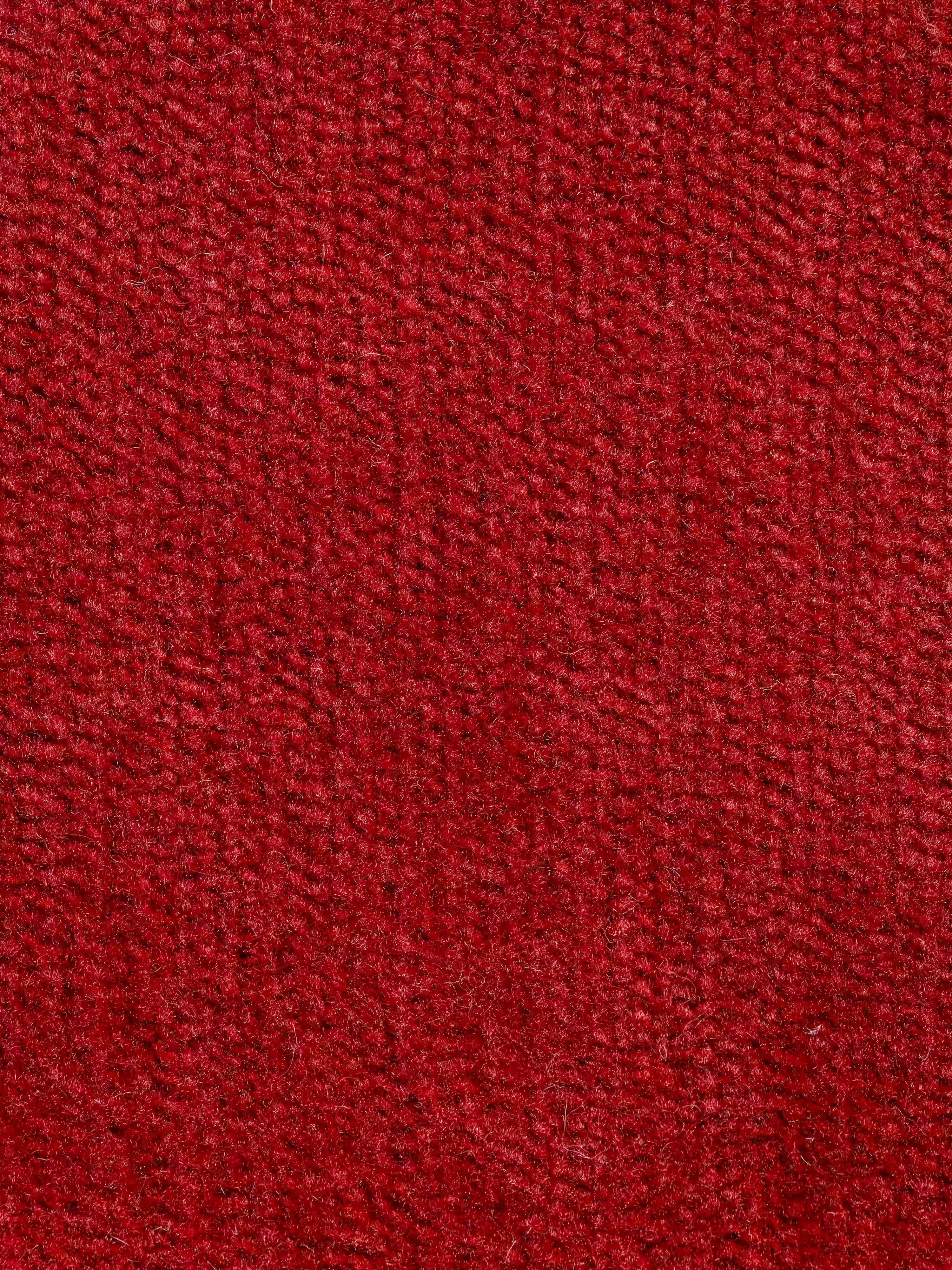 Primo piano del rivestimento rosso e testurizzato del divano letto Miryam con poggiatesta reclinabili e comfort maxi di Divani.Store, realizzato in tessuto T31 smacchiabile, dalla trama fitta e uniforme. Il materiale appare morbido e soffice, con sottili variazioni di tonalità create dalla luce e dalla direzione delle fibre. Non sono visibili macchie né motivi aggiuntivi: solo la raffinata trama intrecciata che si abbina perfettamente a uno stile contemporaneo minimalista.