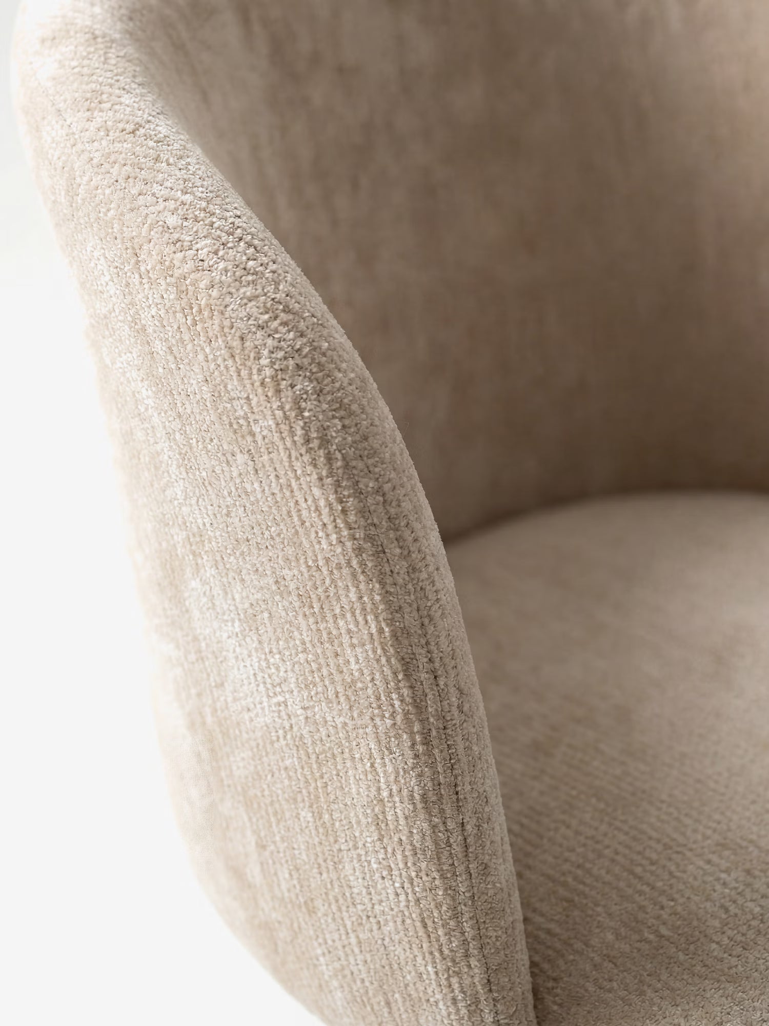 Primo piano della sedia moderna imbottita Talia di Divani.Store, realizzata in morbido tessuto ciniglia beige certificato OEKO-TEX® e dotata di una base abbinata. L'immagine mette in risalto le sue curve eleganti e il design accogliente e senza cuciture su uno sfondo bianco minimalista.