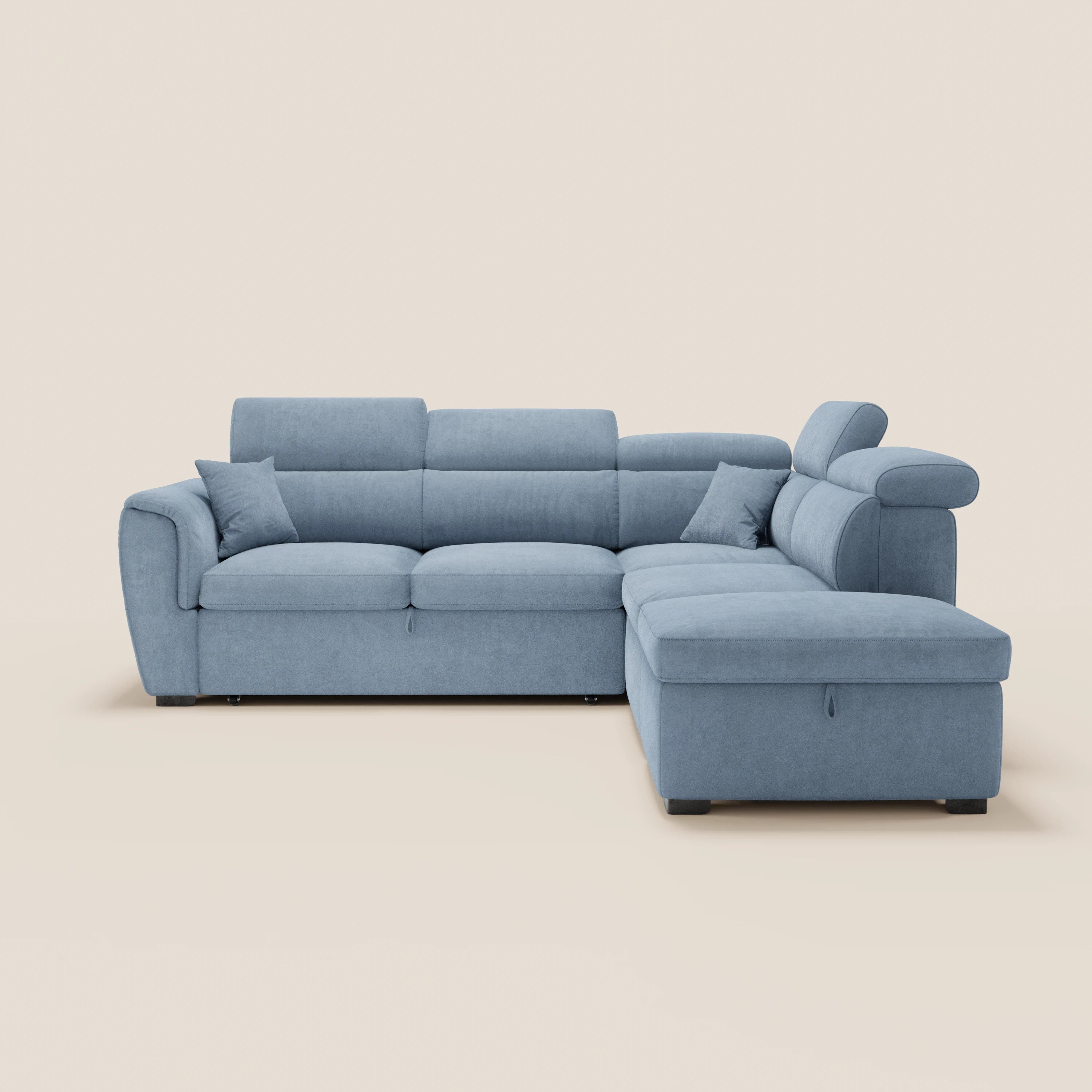 Il divano angolare reversibile Titano di Divani.Store, in azzurro, con due cuscini coordinati, sedute imbottite, ampi braccioli, poggiatesta reclinabili e piedini neri corti, è raffigurato su uno sfondo bianco sporco a tinta unita. Tra le caratteristiche figurano un elemento estraibile e un pouf contenitore.