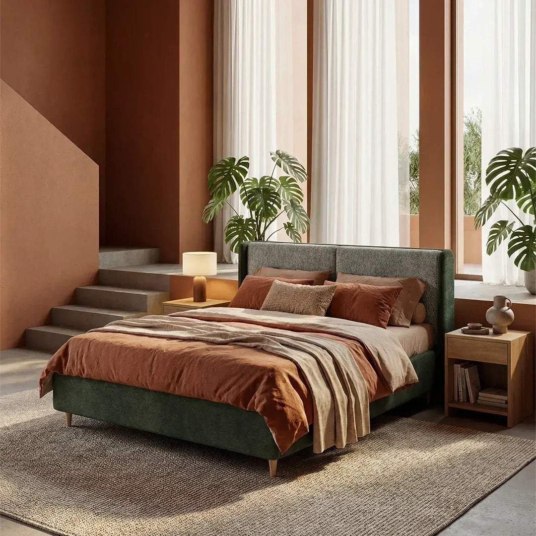 Una camera da letto moderna, con pareti dai toni caldi del marrone, ampie finestre, piante verdi, due comodini in legno e un tappeto beige, ospita il letto imbottito bicolore VALKIRIA di Letti.store, dotato di vano contenitore, testiera ricurva e cuscini per lo schienale.