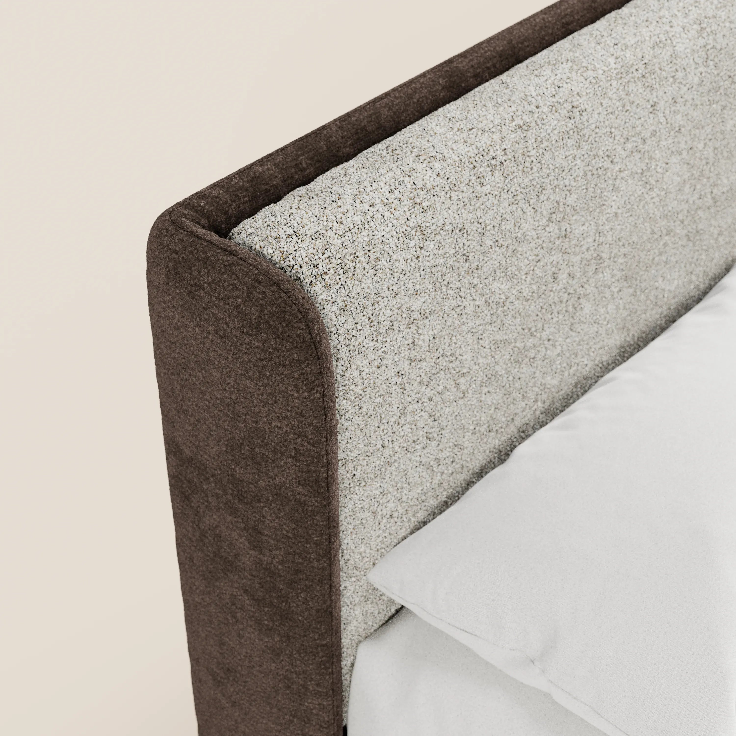 Primo piano del letto imbottito bicolore VALKIRIA di Letti.store: presenta una testiera curva rivestita in tessuto grigio chiaro con finiture marrone scuro, cuscino e lenzuolo bianchi, il tutto su uno sfondo beige chiaro.