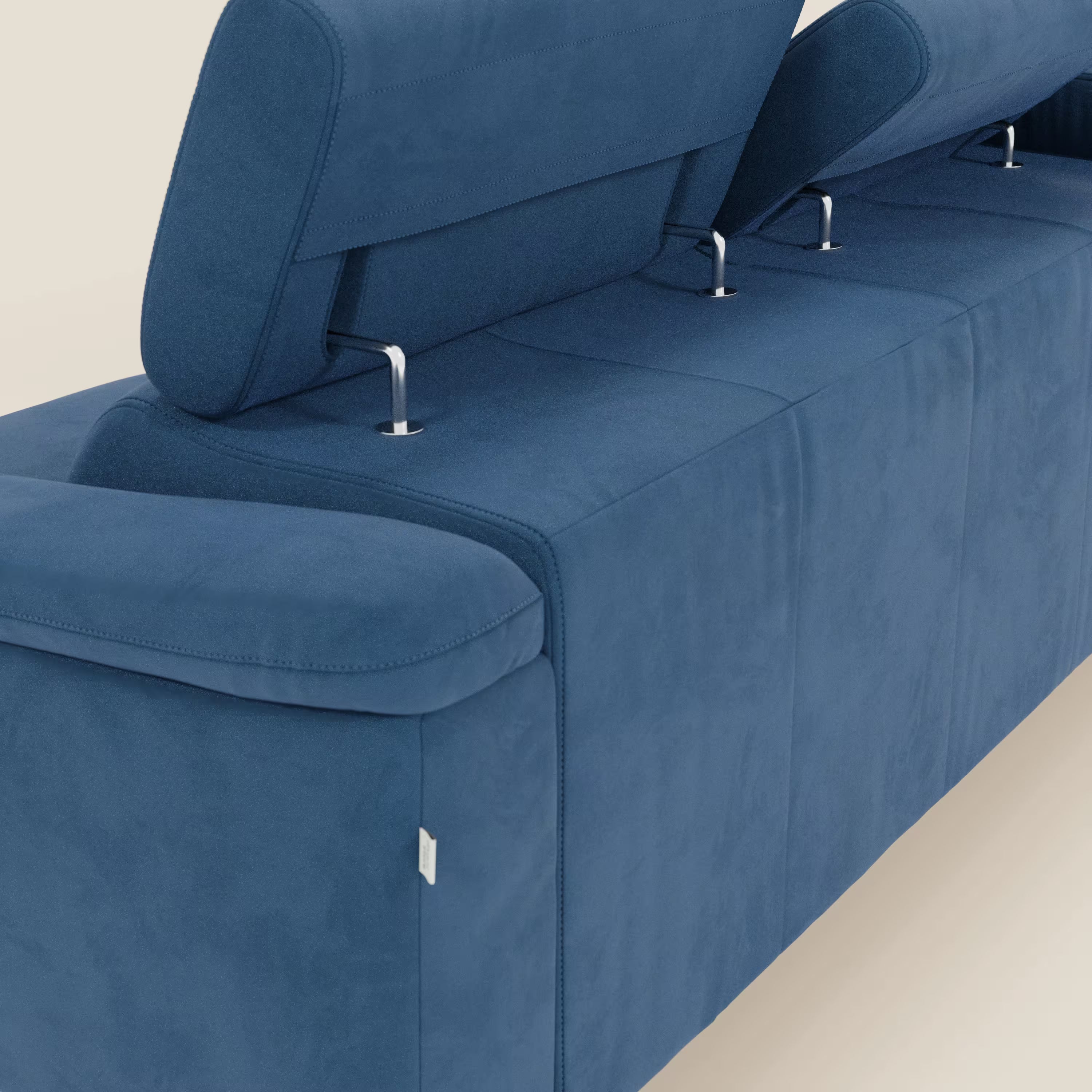 Primo piano dell'Arcos Divano con penisola di Divani.Store in microfibra impermeabile blu T11, con gambe alte e poggiatesta regolabile. Le linee pulite, la morbida imbottitura e la sottile etichetta del tessuto spiccano su uno sfondo beige chiaro per un comfort rilassante.